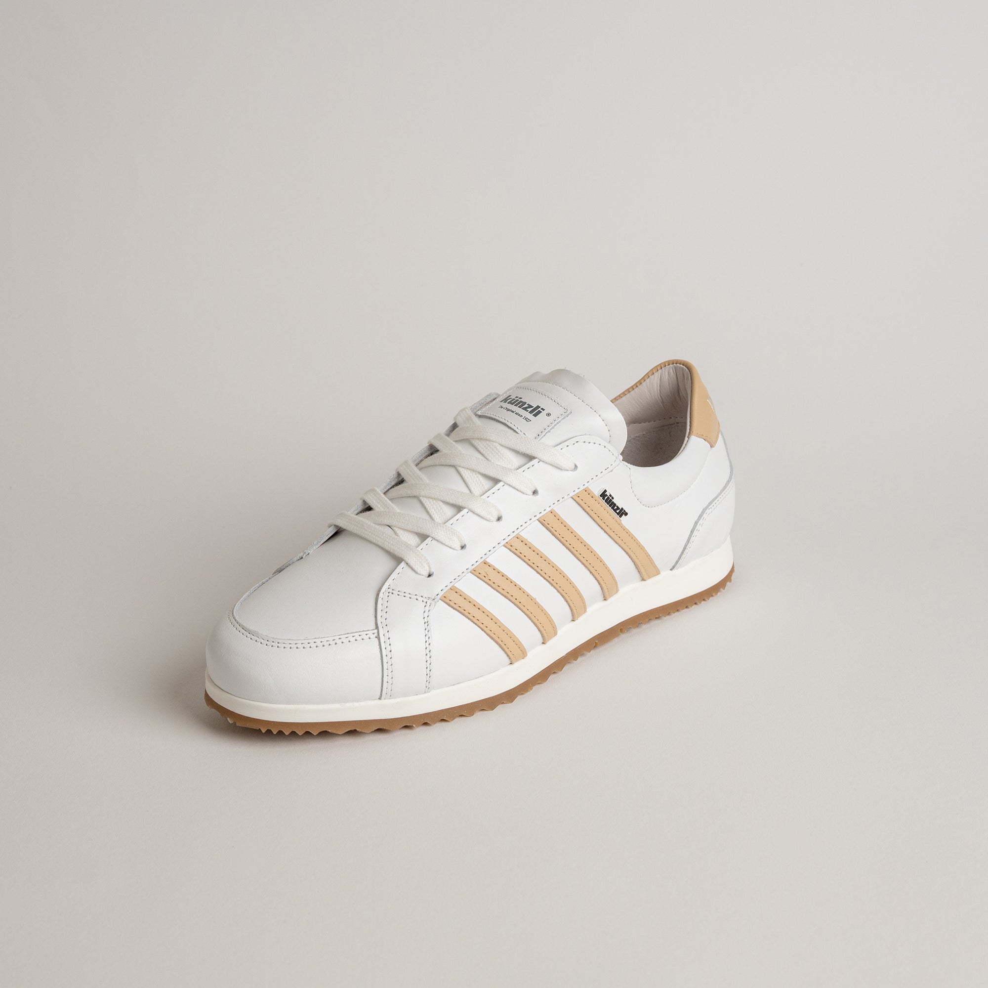 Weißer Kuenzli Schuh mit beigen Streifen auf neutralem Hintergrund, ideal für Freizeitaktivitäten.