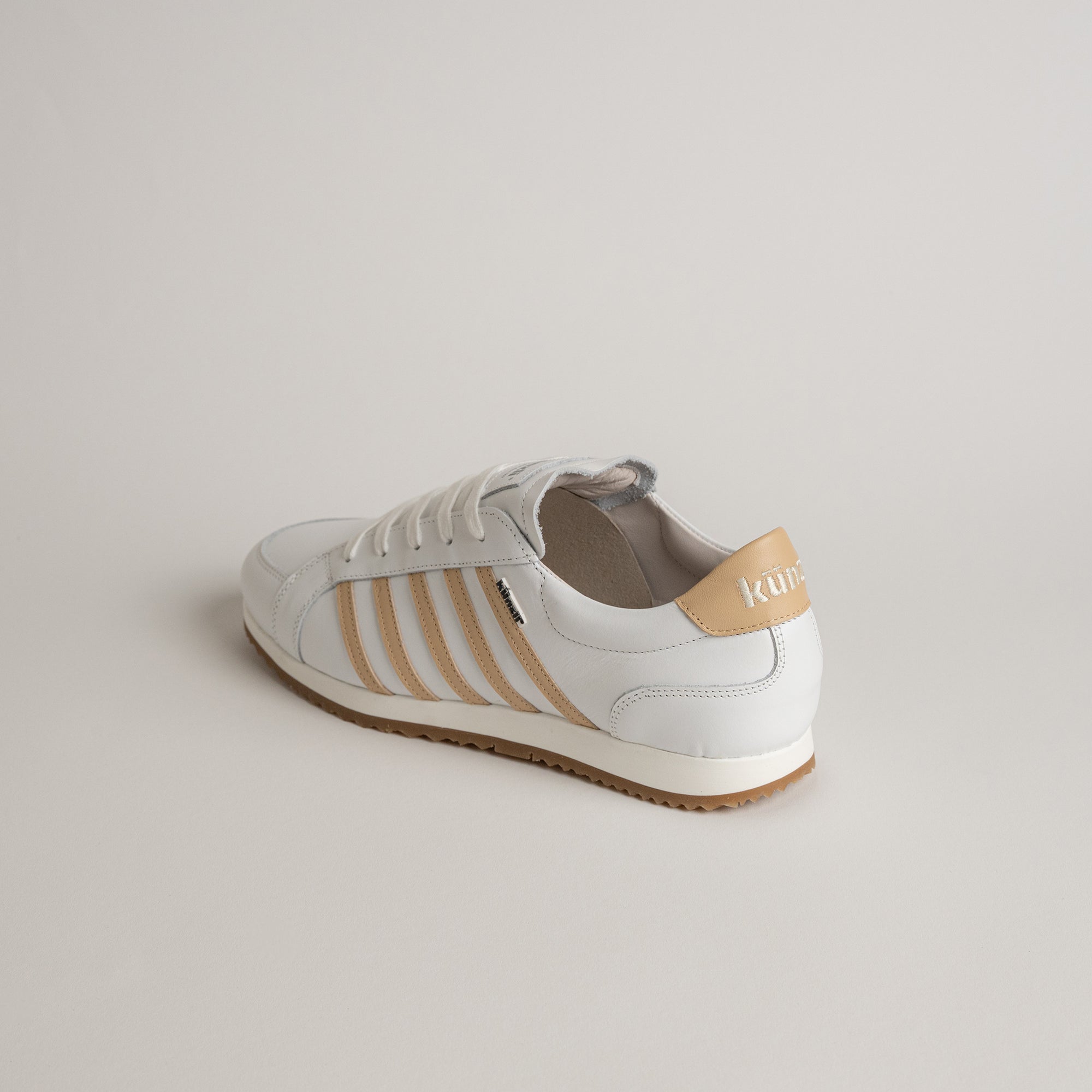 Weißer Lederschuh von Kuenzli Schuhe mit beigen Streifen auf hellem Hintergrund.