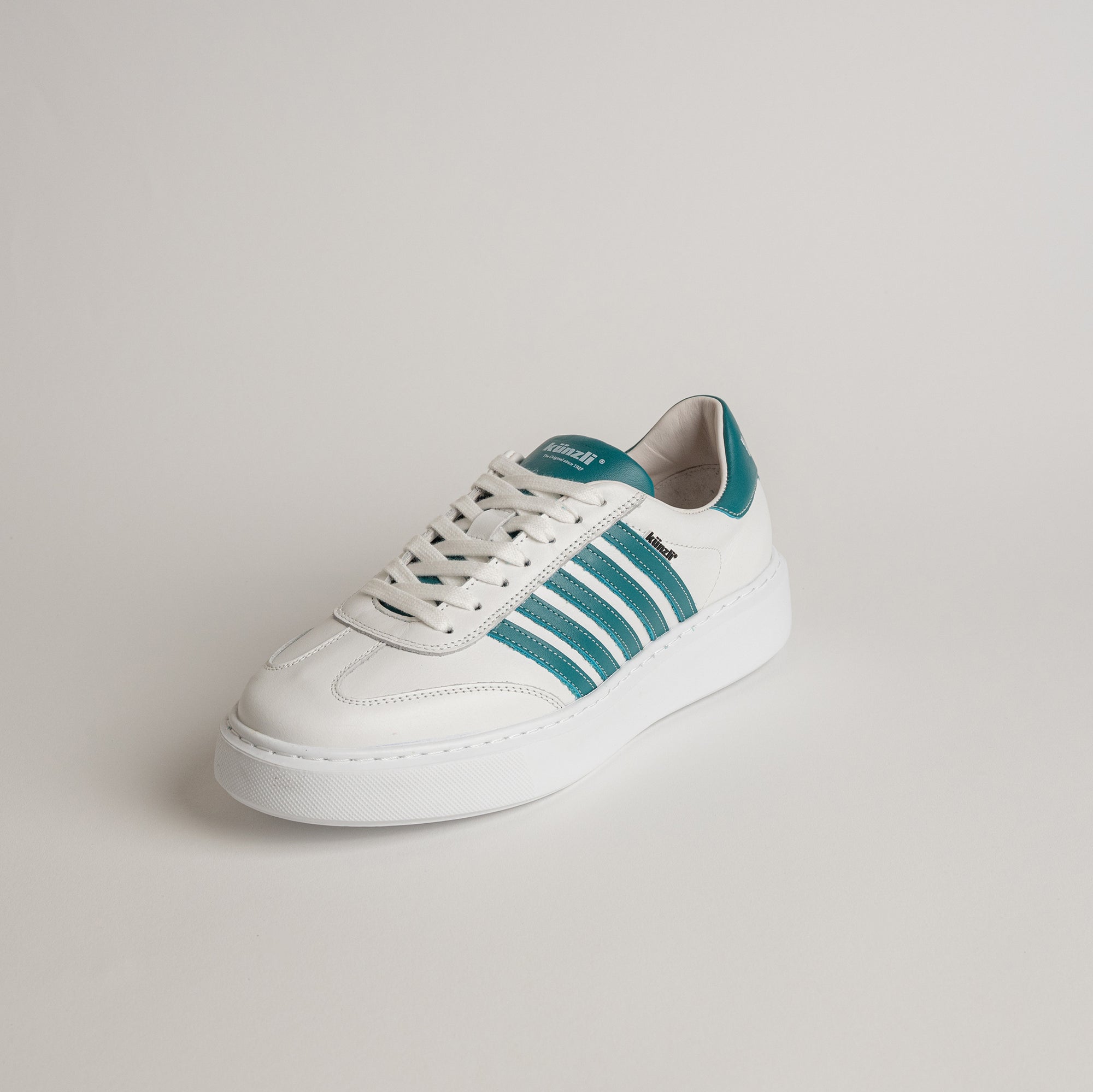 Weißer Kuenzli Schuh mit grünen Streifen auf hellem Hintergrund, sportlich und modern.
