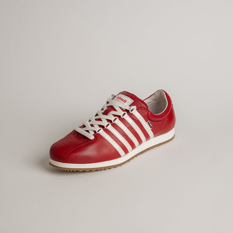 Roter Kuenzli Schuh aus Leder mit weißen Streifen auf hellem Hintergrund.
