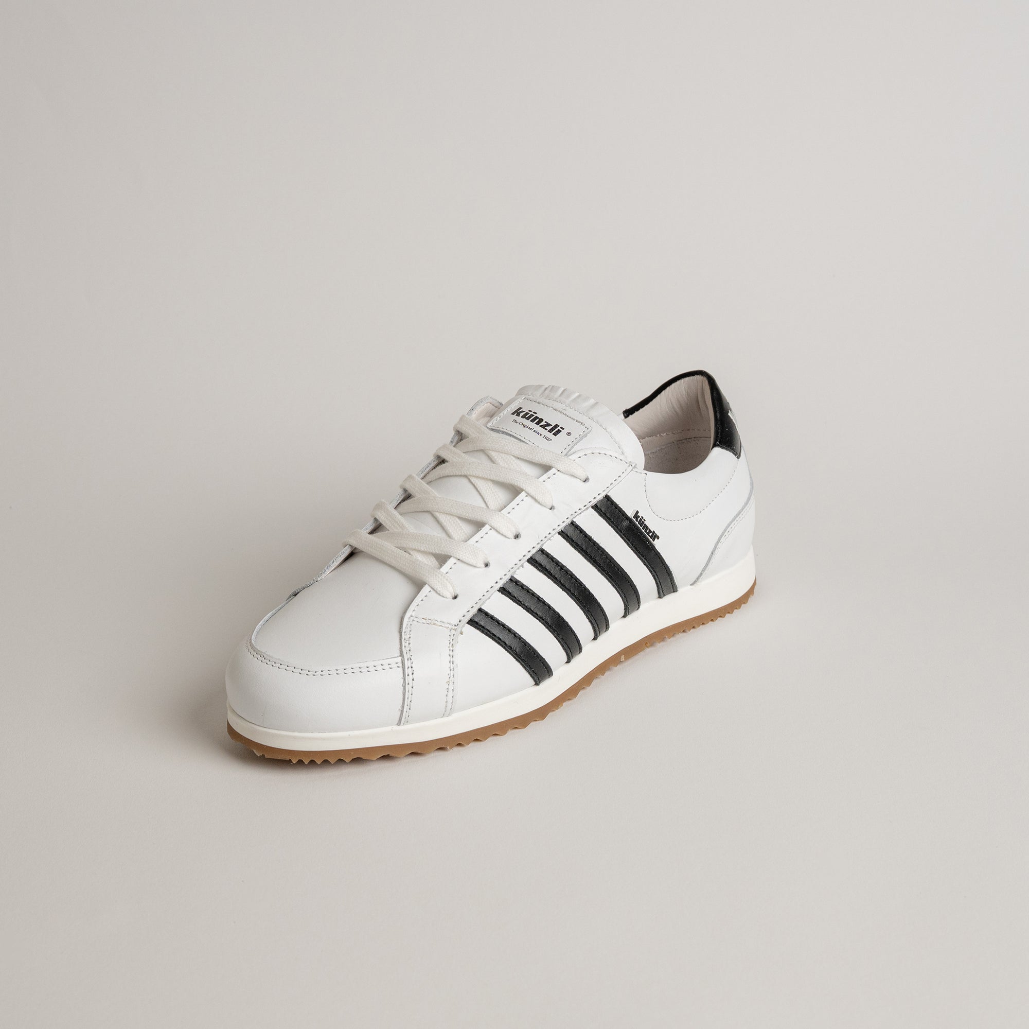 Weißer Kuenzli Schuh mit schwarzen Streifen auf hellem Hintergrund, ideal für Sport und Freizeit.