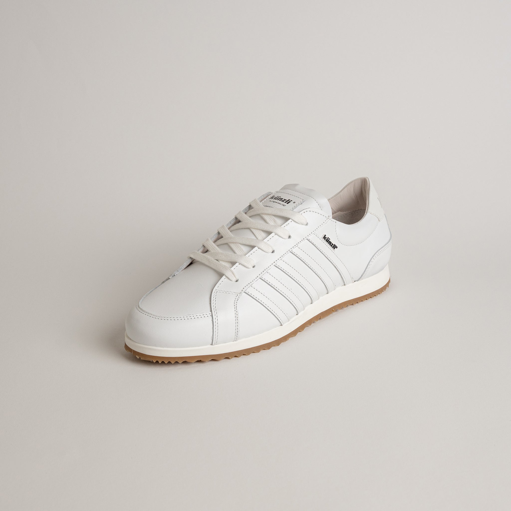 Weißer Kuenzli Schuhe Sneaker aus Leder mit brauner Sohle auf hellem Hintergrund.