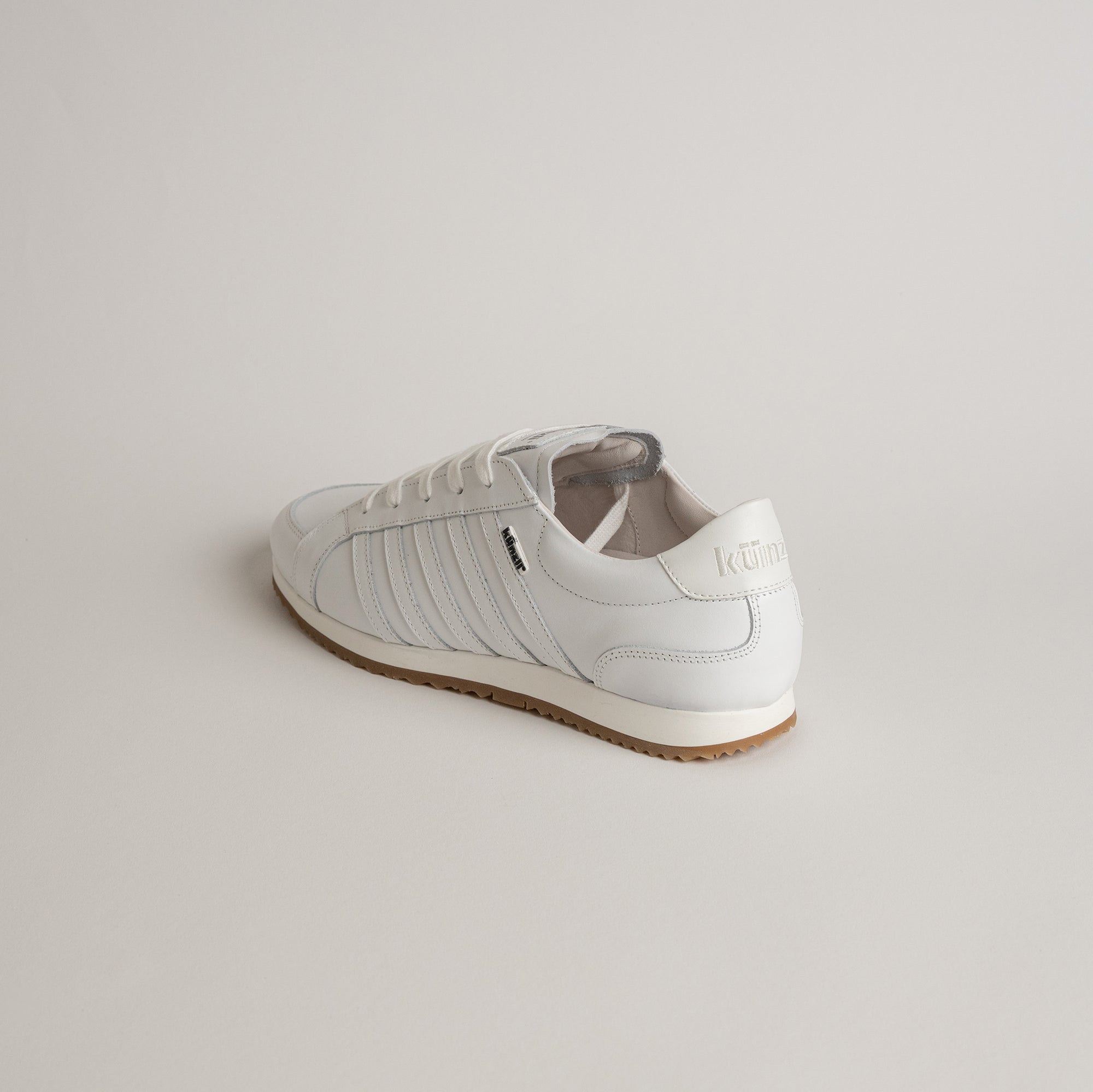 Weißer Lederschuh von Kuenzli Schuhe auf hellem Hintergrund, seitlich fotografiert.