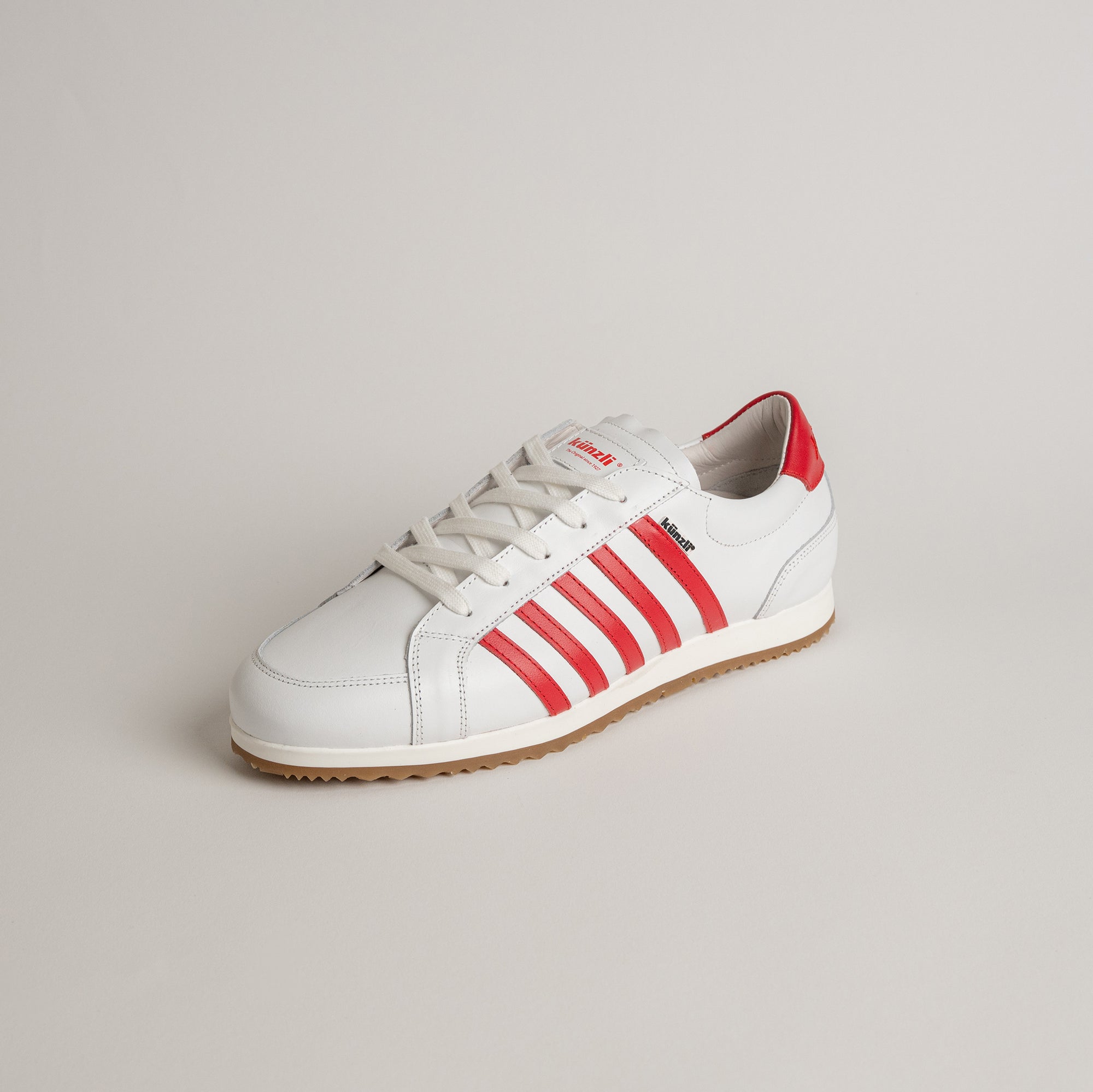 Weißer Kuenzli Schuh mit roten Streifen auf hellem Hintergrund.