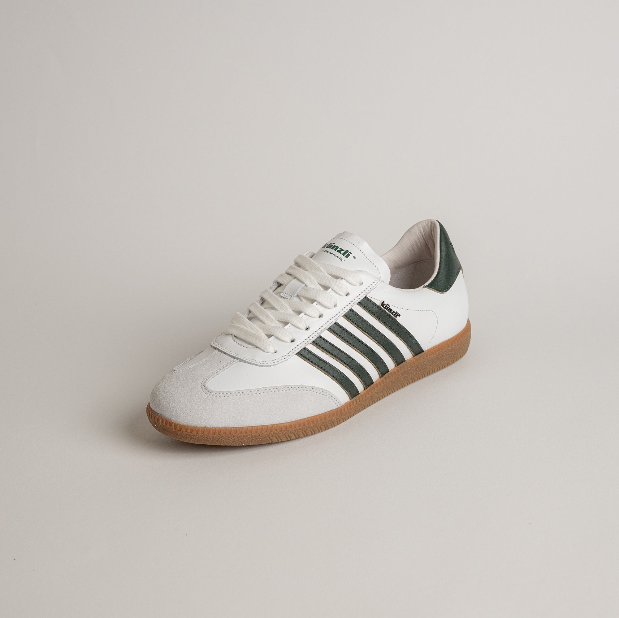 Weißer Kuenzli Schuh mit grünen Streifen und brauner Sohle auf neutralem Hintergrund.