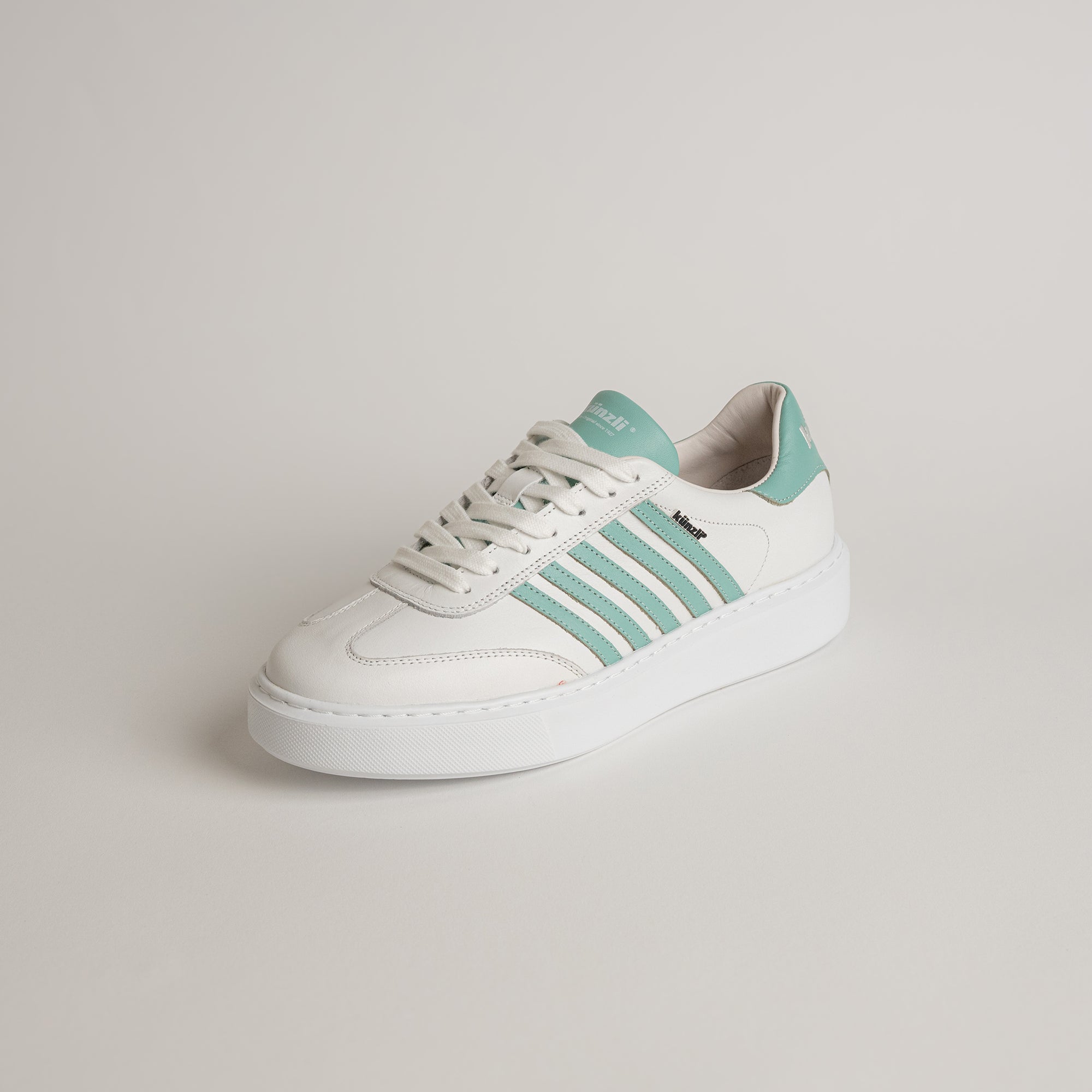 Weißer Sneaker von Kuenzli Schuhe mit mintgrünen Streifen auf hellem Hintergrund.