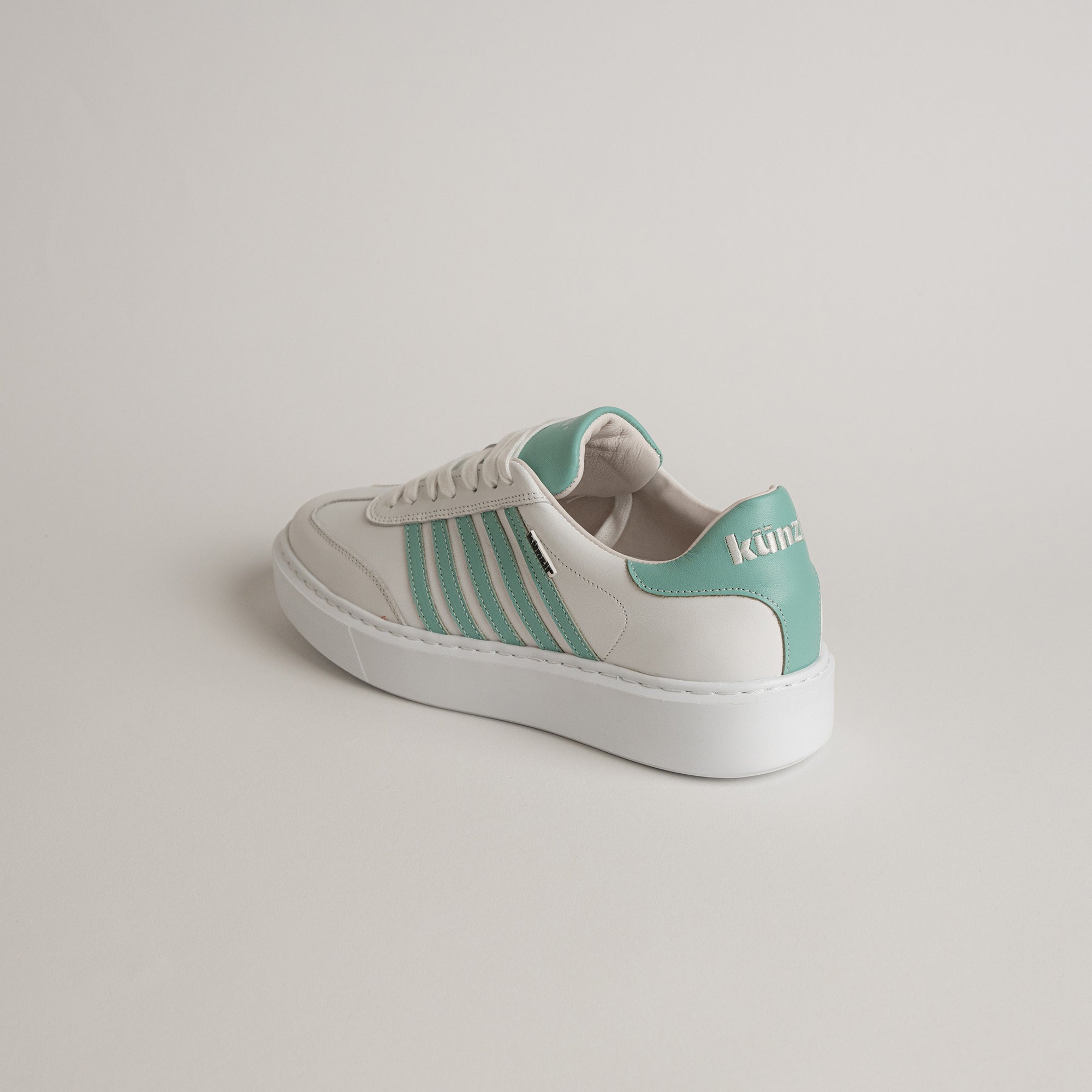 Weißer Sneaker mit grünen Details von Kuenzli Schuhe auf hellem Hintergrund.