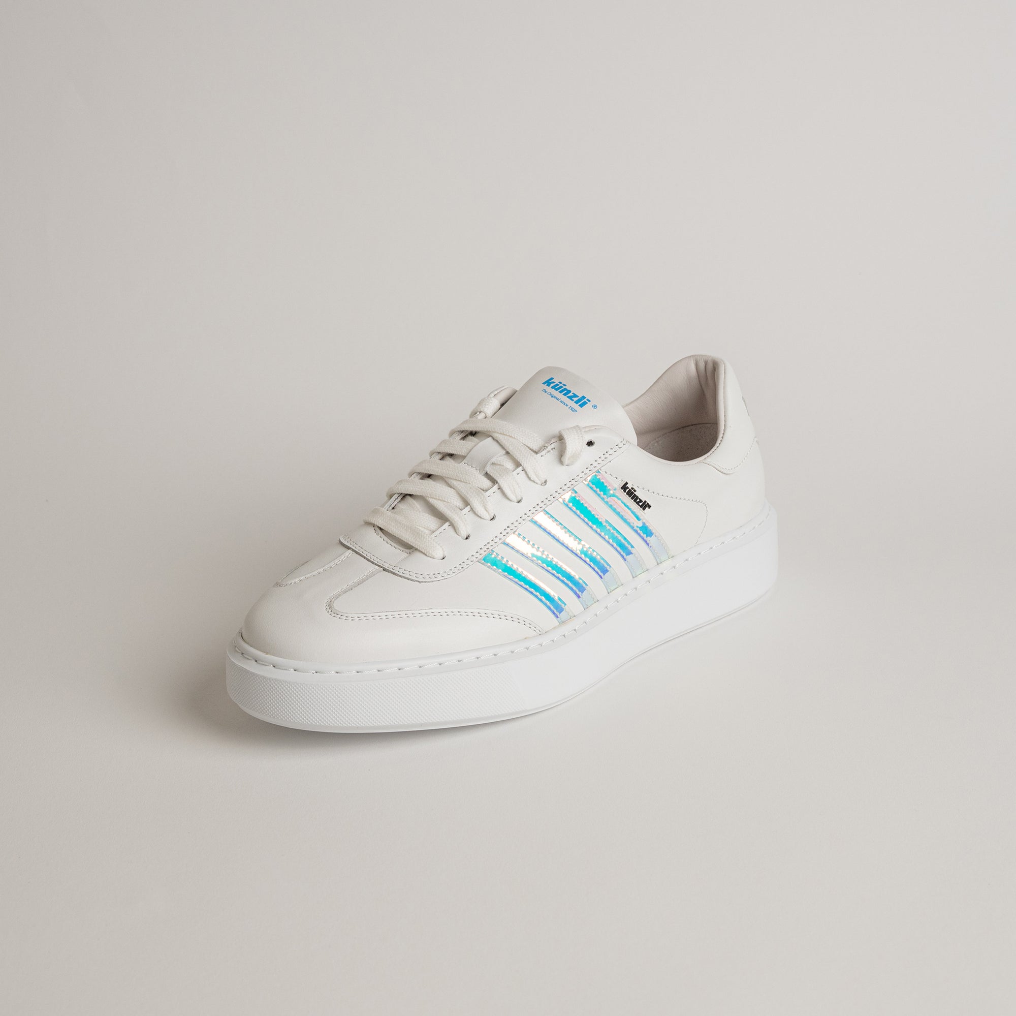 Weißer Ledersneaker von Kuenzli Schuhe mit blauen Streifen auf hellem Hintergrund.