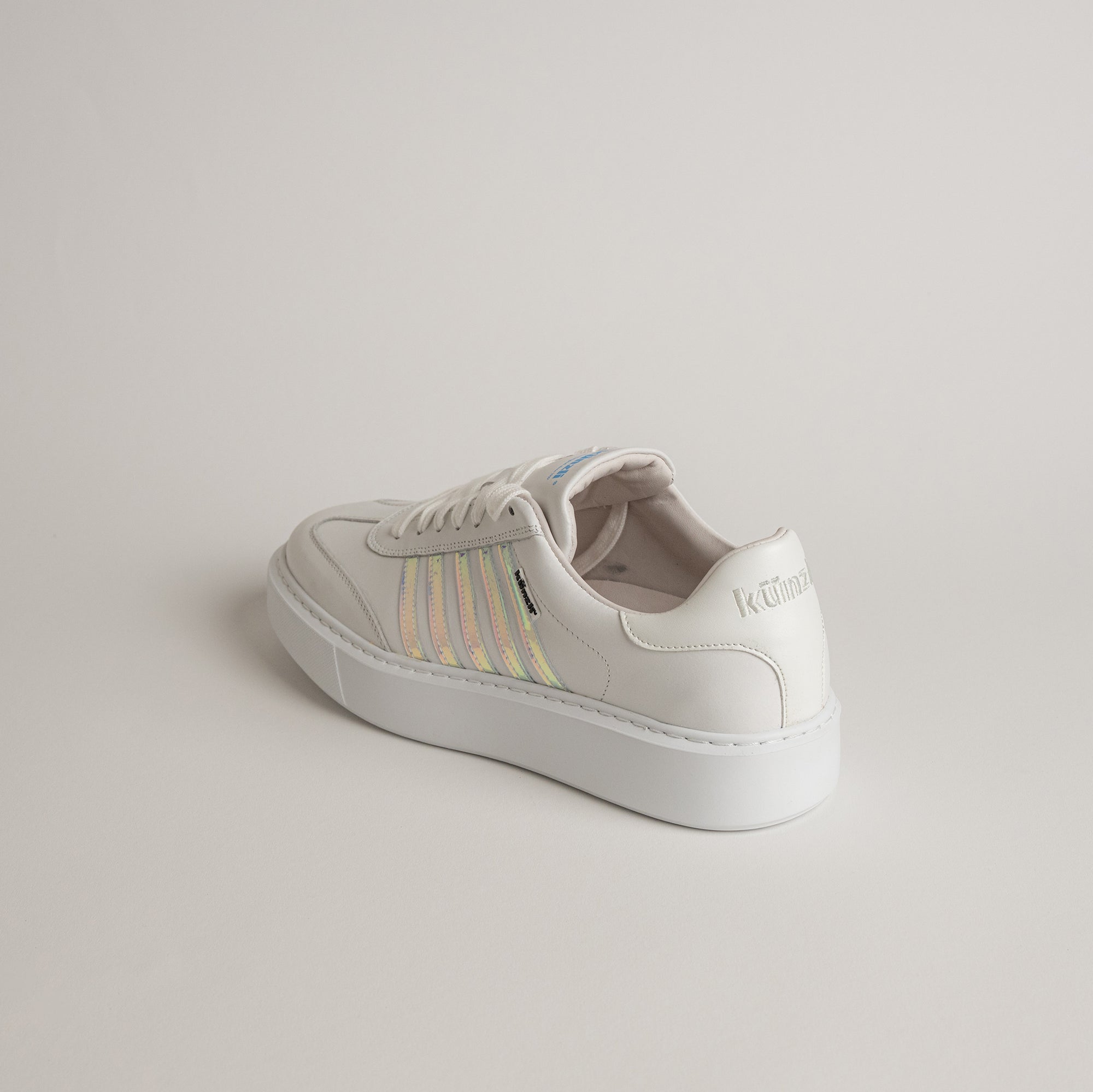 Ein weißer Kuenzli Schuh mit schimmernden Streifen auf hellem Hintergrund.