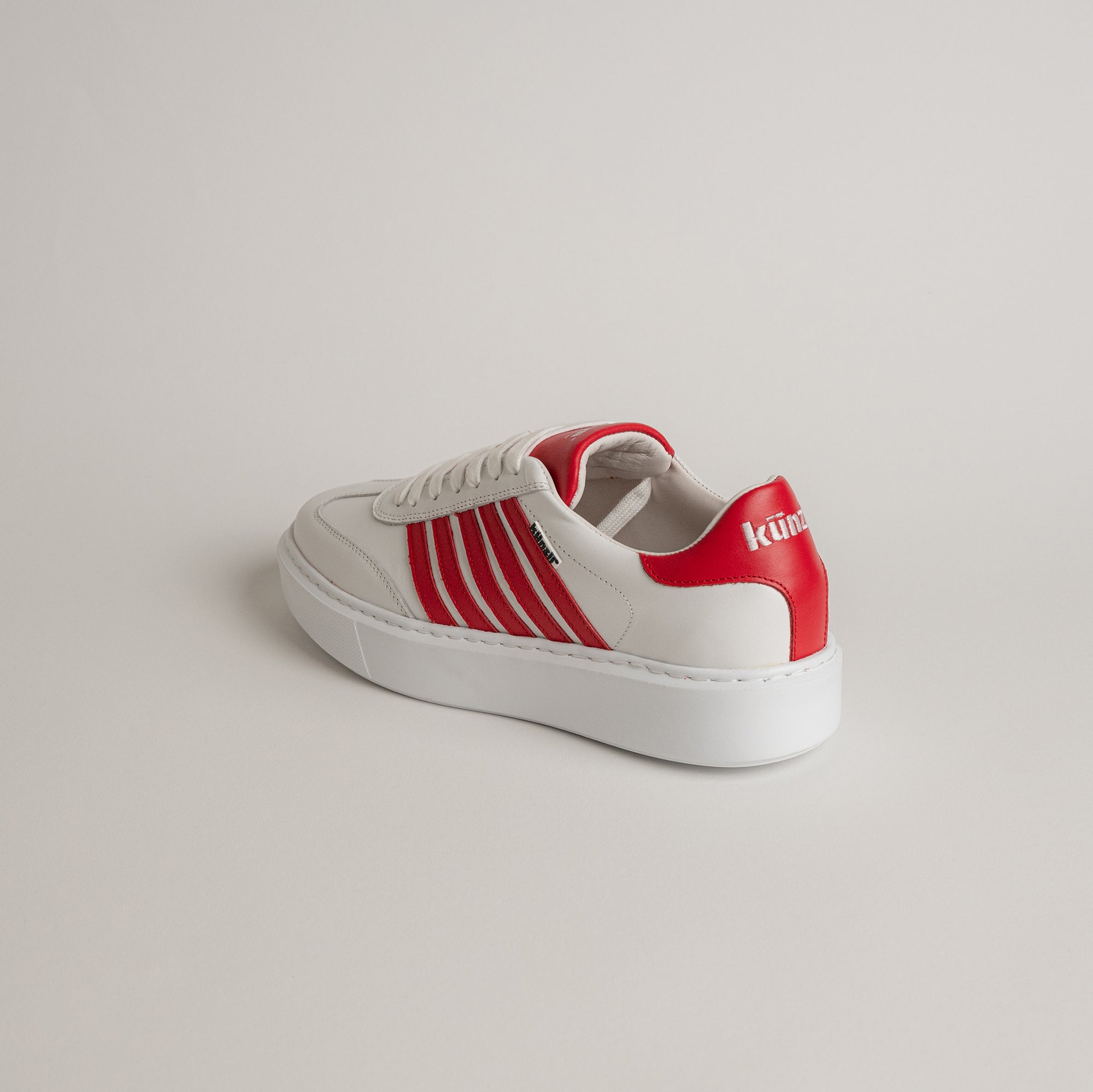Weißer Sneaker mit roten Details von Kuenzli Schuhe auf hellem Hintergrund.