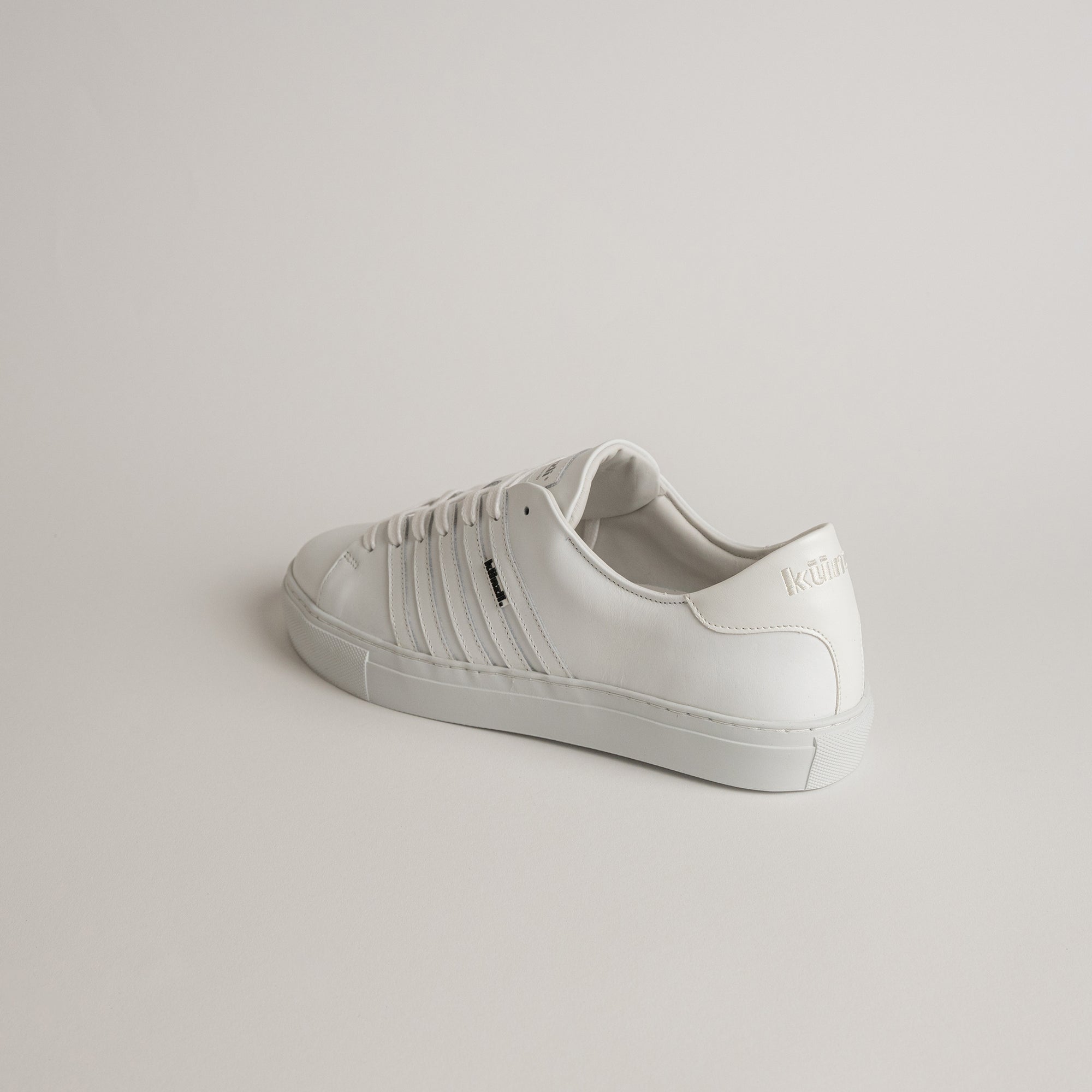Weißer Ledersneaker von Kuenzli Schuhe auf neutralem Hintergrund, seitlich präsentiert.