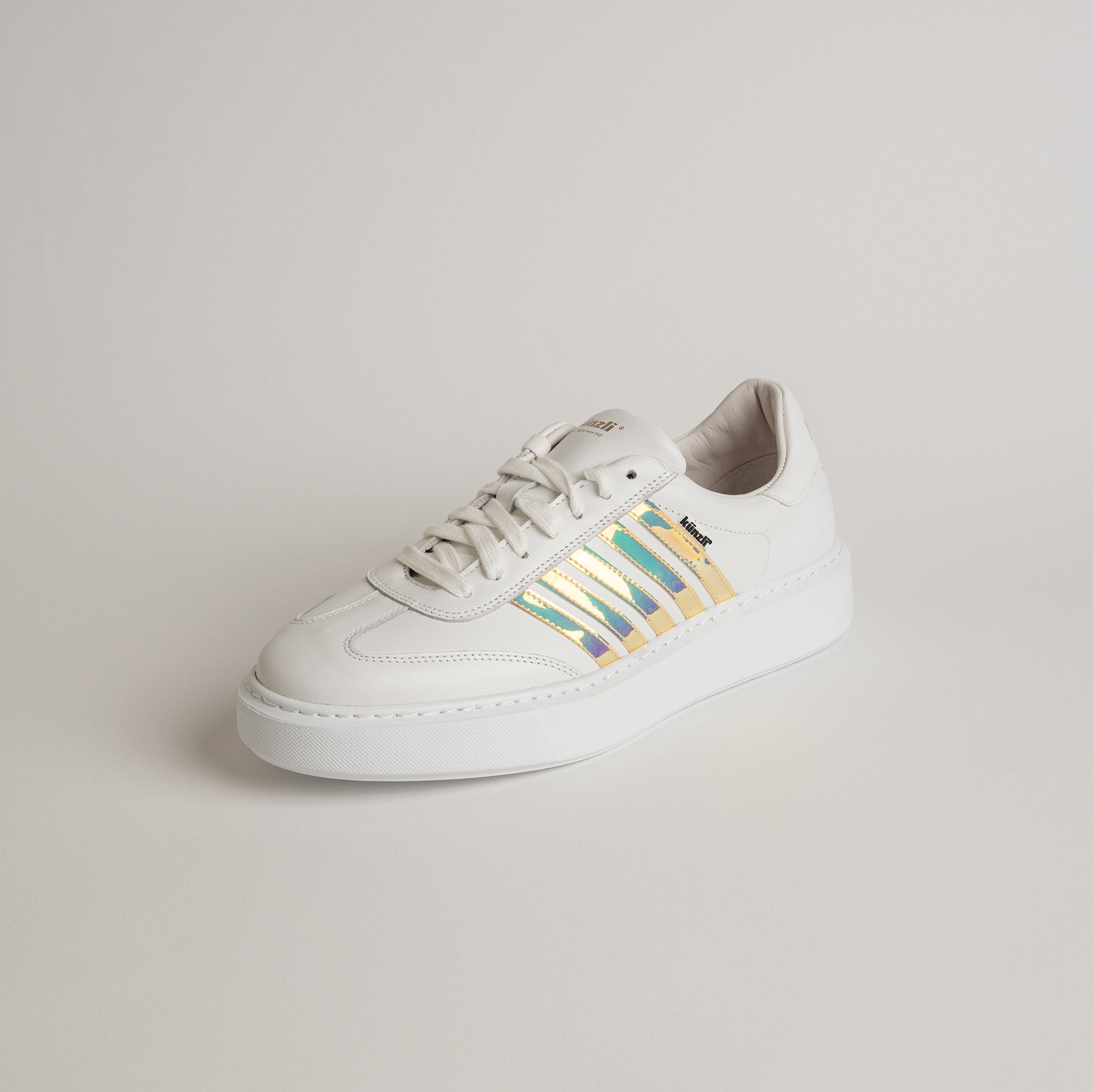 Weißer Sneaker von Kuenzli Schuhe mit schillernden Streifen auf hellem Hintergrund.