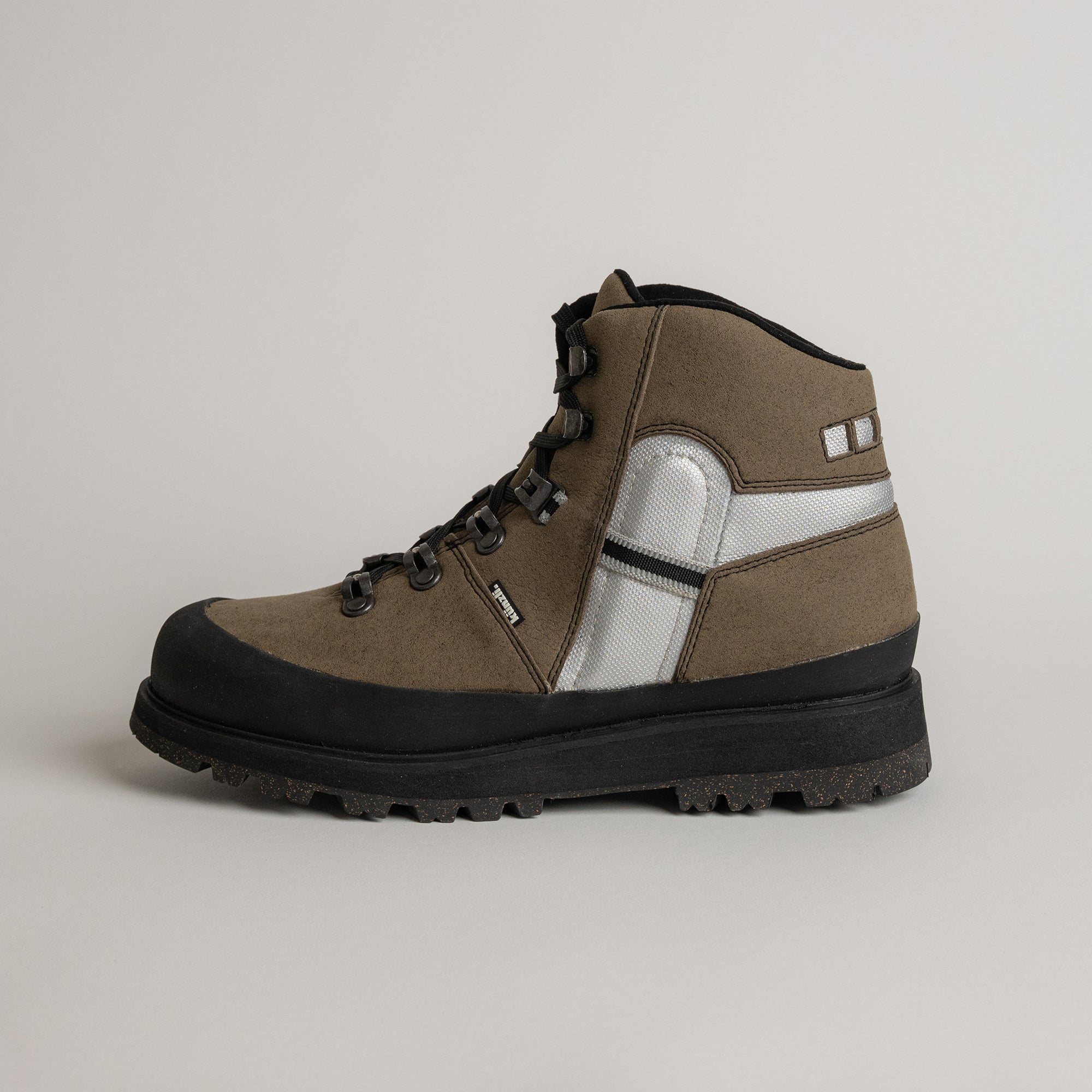 Brauner Wanderschuh von Kuenzli Schuhe mit robustem Profil und silbernen Details.