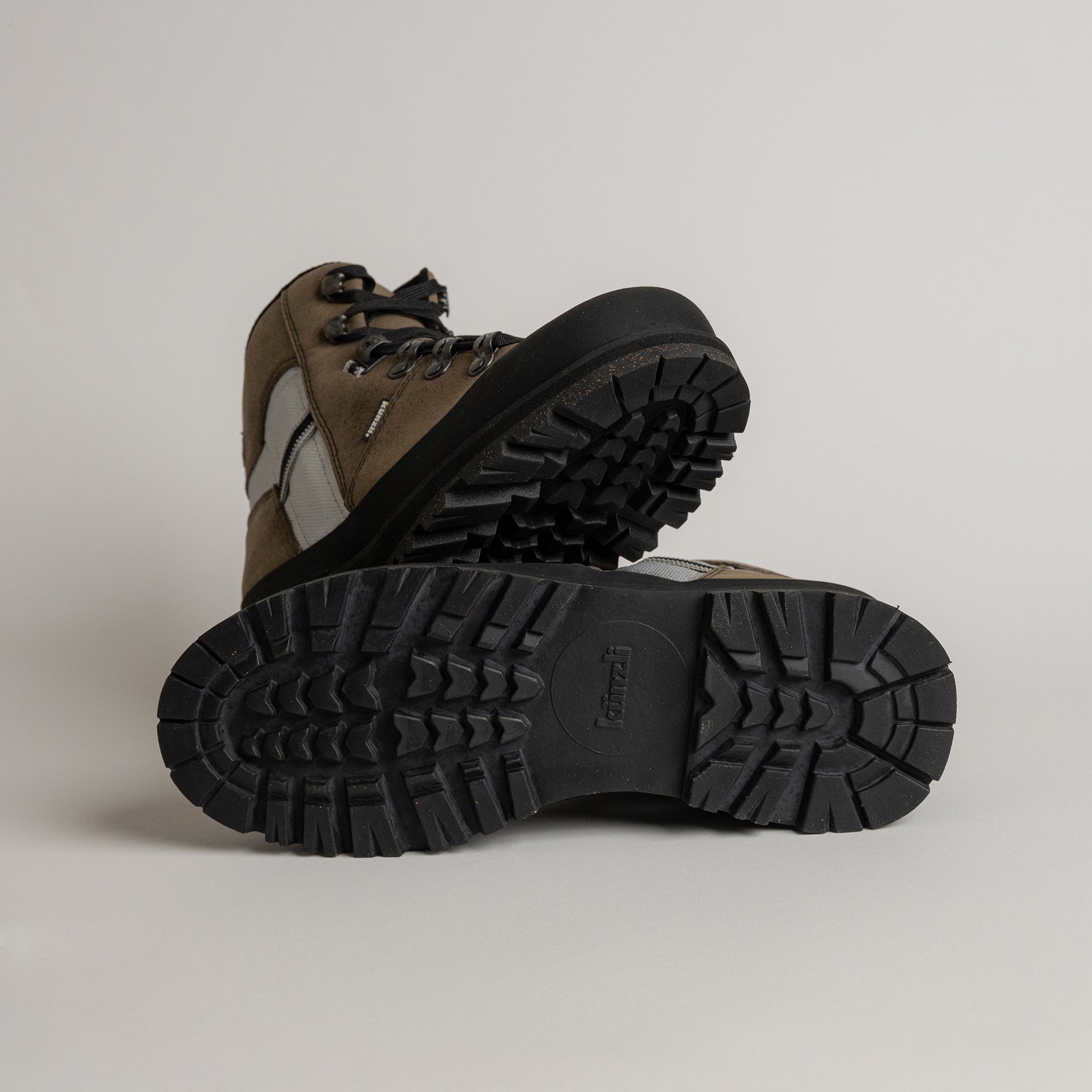 Braune Wanderschuhe von Kuenzli Schuhe mit robuster Profilsohle auf grauem Hintergrund.