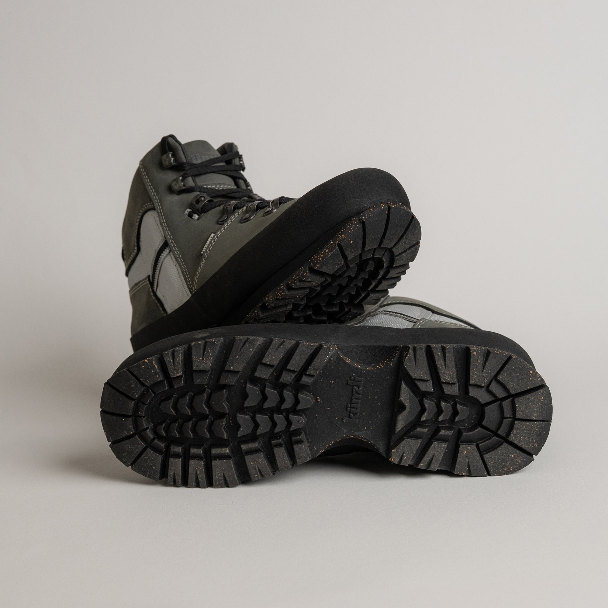 Graue Wanderschuhe von Kuenzli Schuhe mit robuster Profilsohle auf grauem Hintergrund.