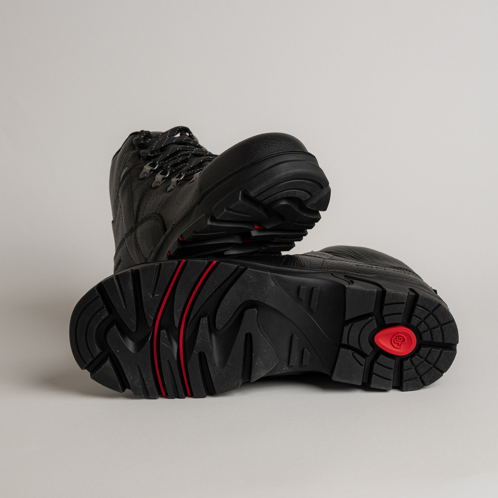 Schwarze Kuenzli Schuhe mit robustem Profil und roten Akzenten auf hellem Hintergrund.