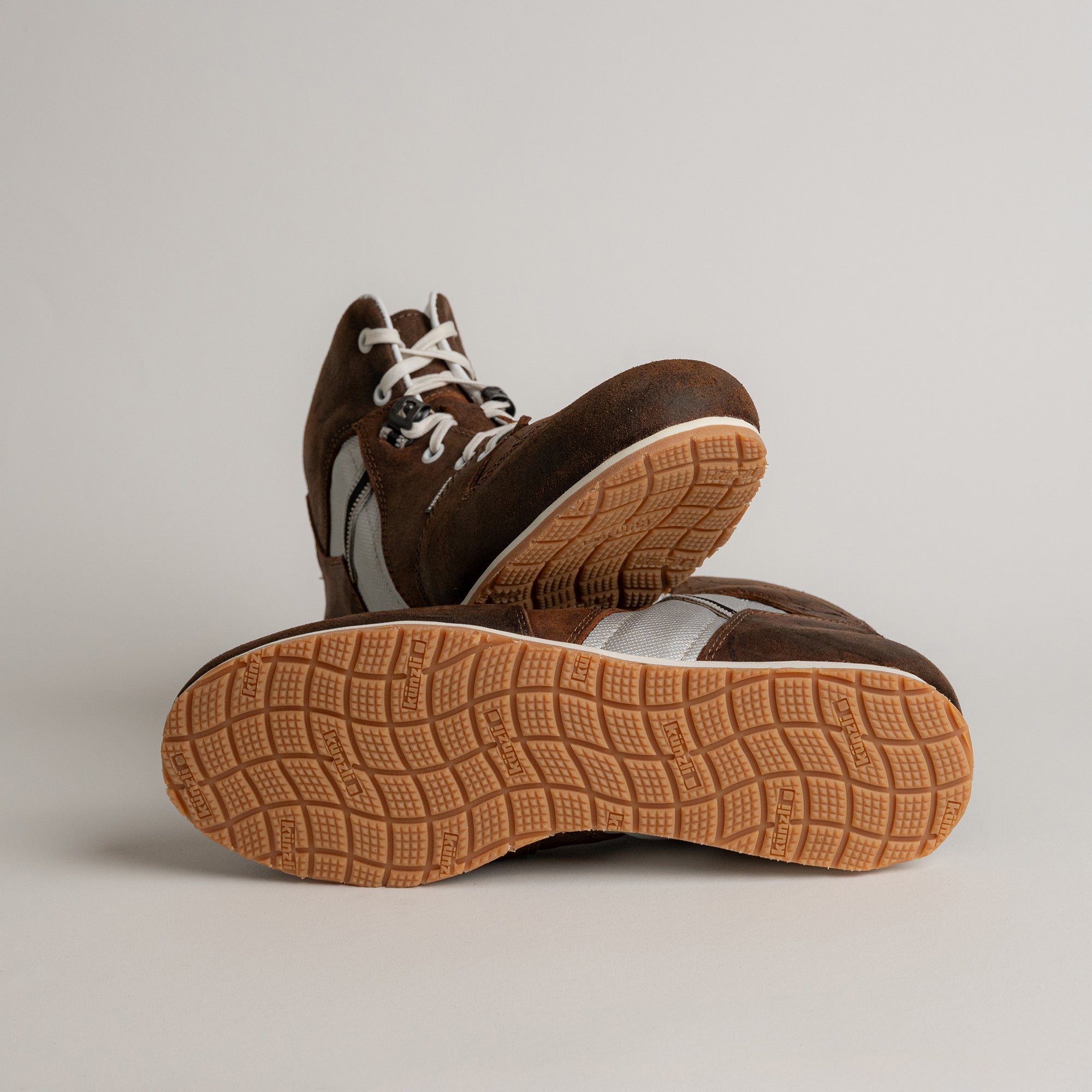 Braune Kuenzli Schuhe aus Leder mit heller Sohle auf grauem Hintergrund.