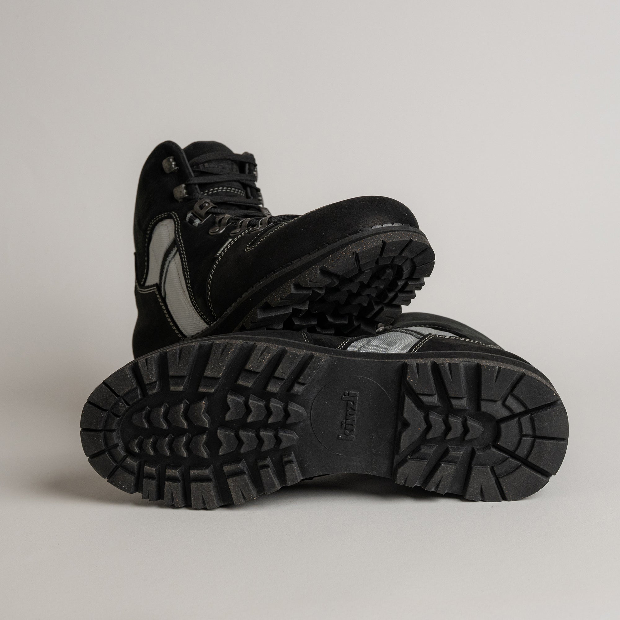 Schwarze Wanderschuhe von Kuenzli Schuhe mit robustem Profil auf grauem Hintergrund.