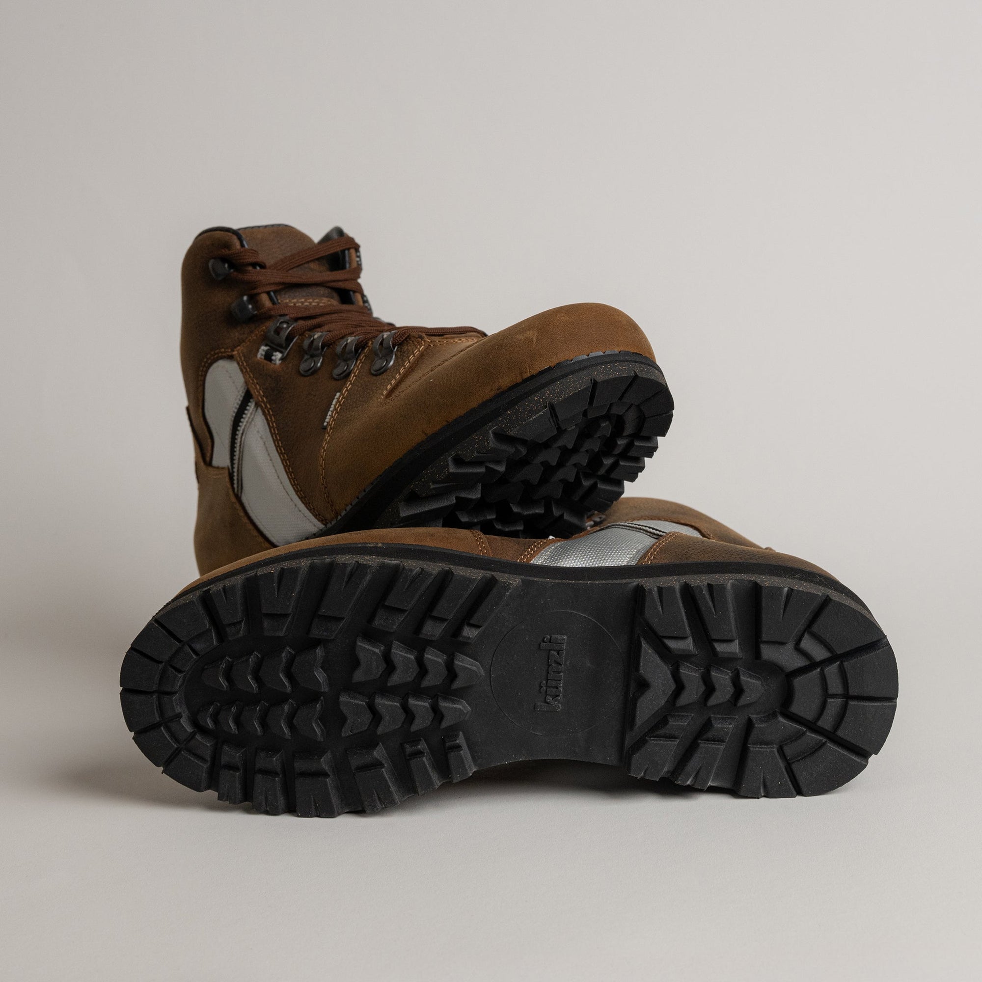 Braune Wanderschuhe von Kuenzli Schuhe mit robuster Sohle auf grauem Hintergrund.