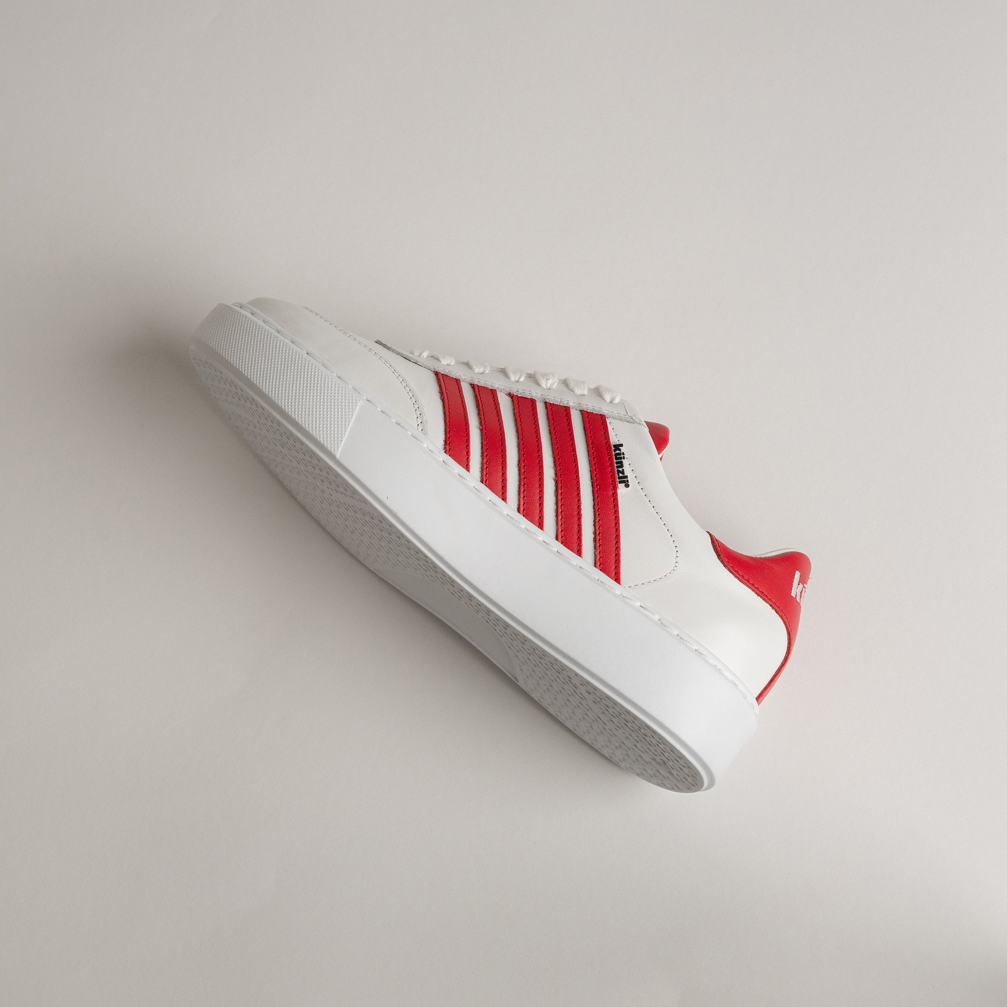Weißer Sneaker mit roten Streifen von Kuenzli Schuhe auf hellem Hintergrund.