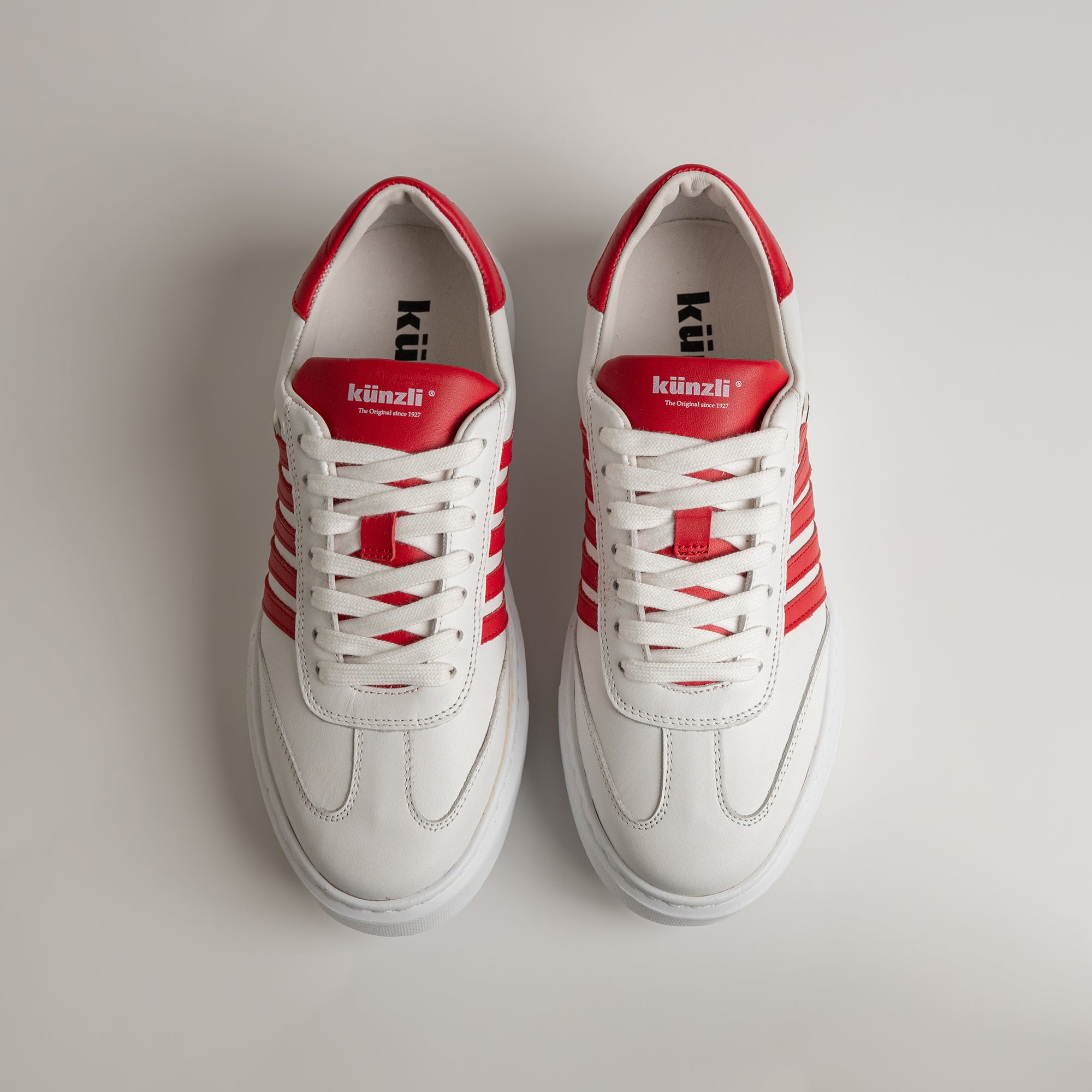 Weiße Kuenzli Schuhe mit roten Streifen auf hellem Hintergrund, sportlich und modern.