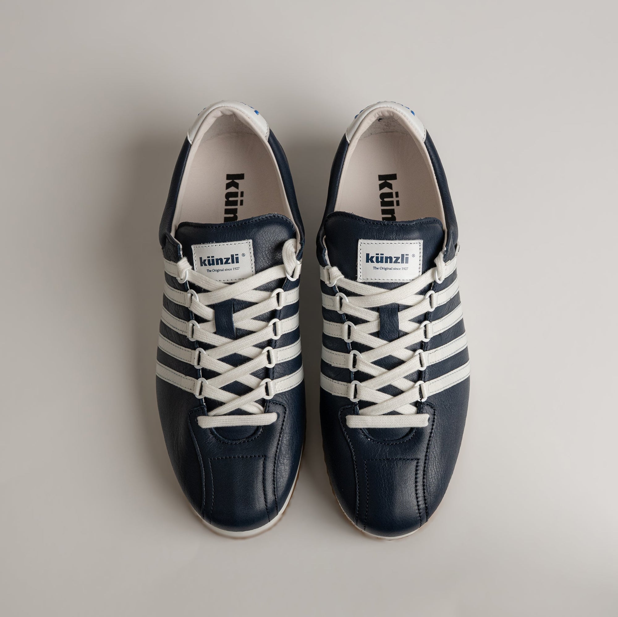 Zwei blaue und weiße Kuenzli Schuhe aus Leder auf hellem Hintergrund.