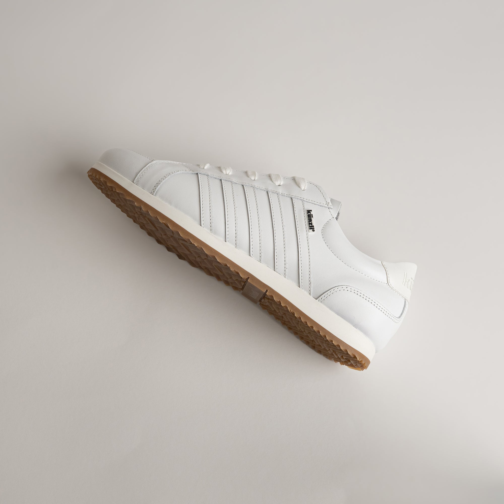 Weißer Lederschuh von Kuenzli Schuhe mit brauner Sohle auf hellem Hintergrund.