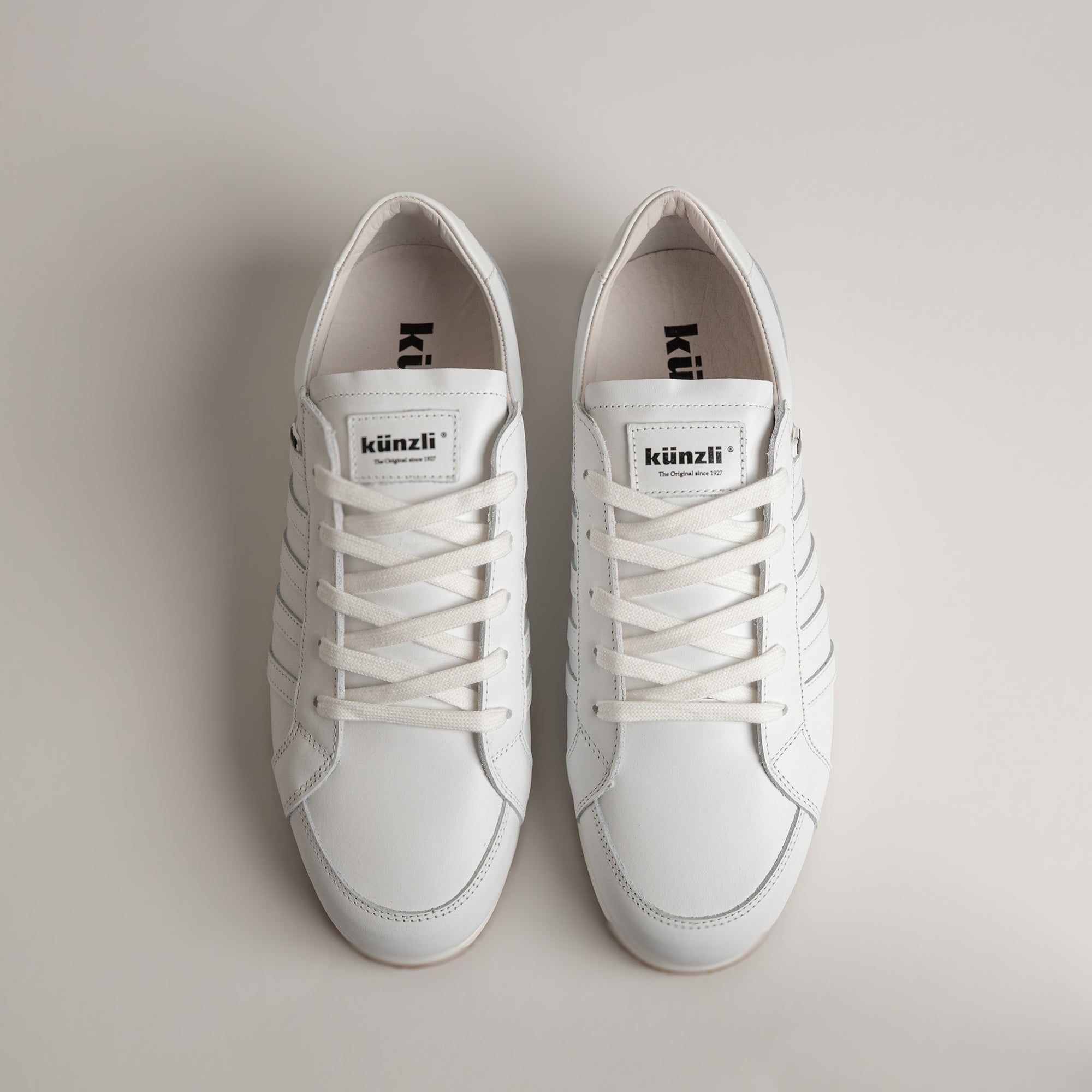 Weiße Kuenzli Schuhe aus Leder mit Schnürsenkeln, auf hellem Hintergrund präsentiert.