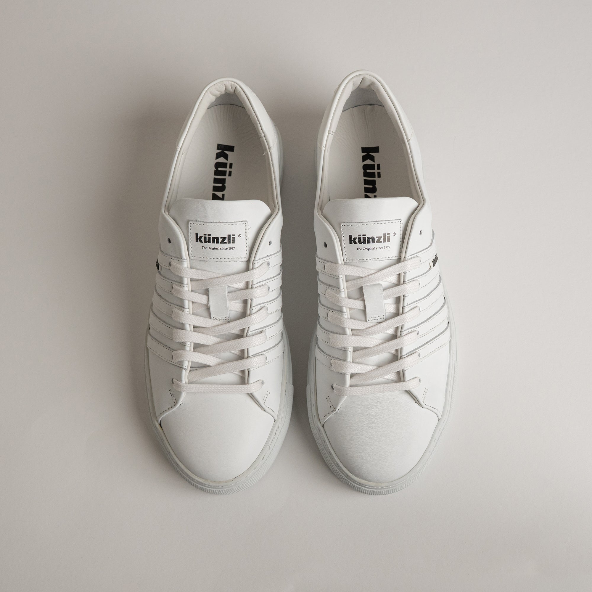 Weiße Kuenzli Schuhe aus Leder mit Schnürsenkeln auf hellem Hintergrund.