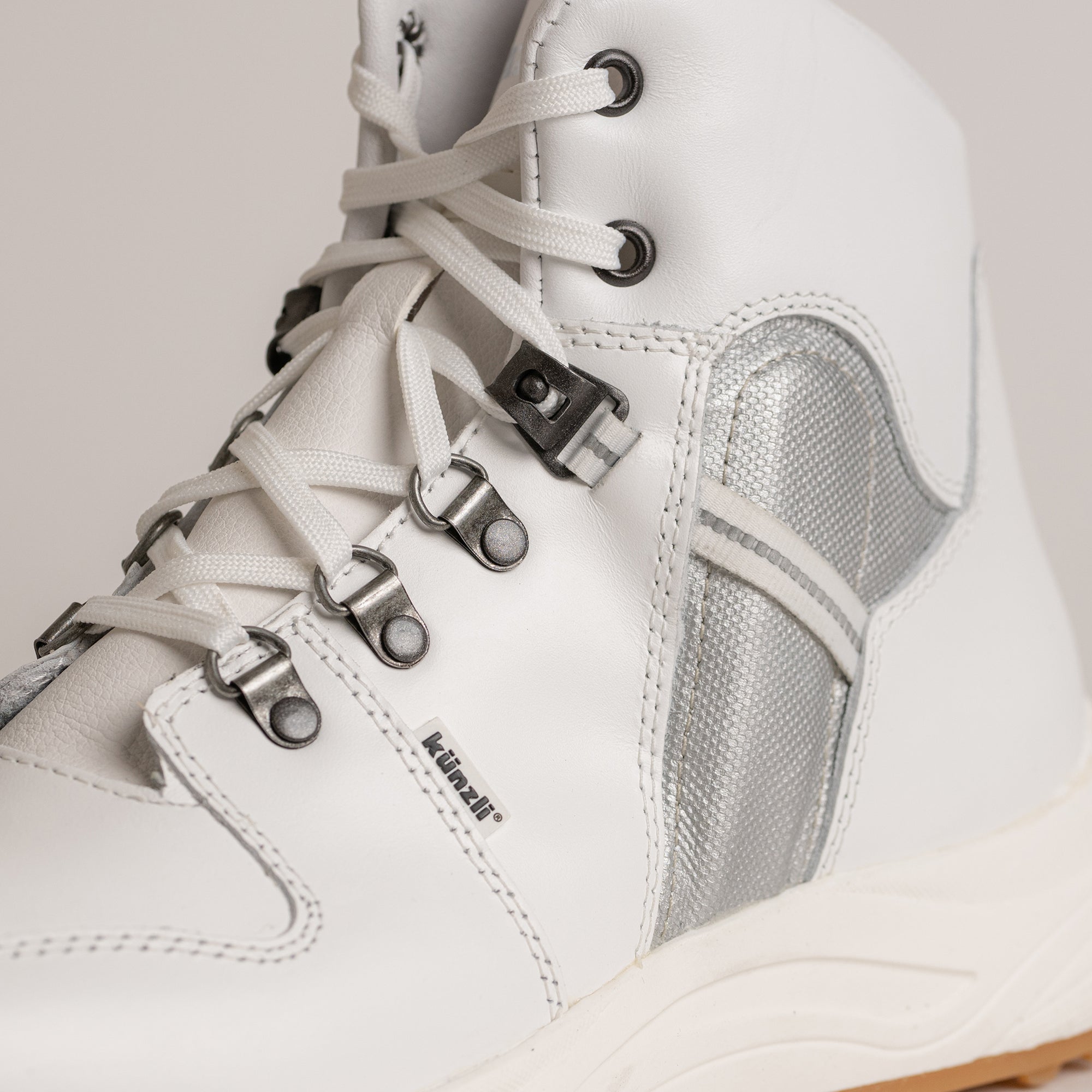 Weißer Kuenzli Schuh aus Leder mit silbernen Details und stabilen Schnürsenkeln.