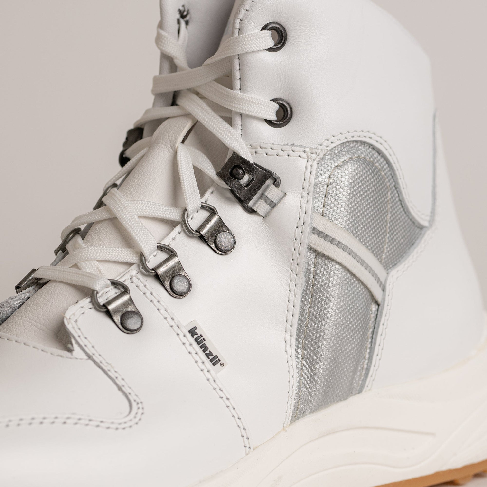 Weißer Kuenzli Schuh mit Metallösen und silbernen Details für Outdoor-Aktivitäten.