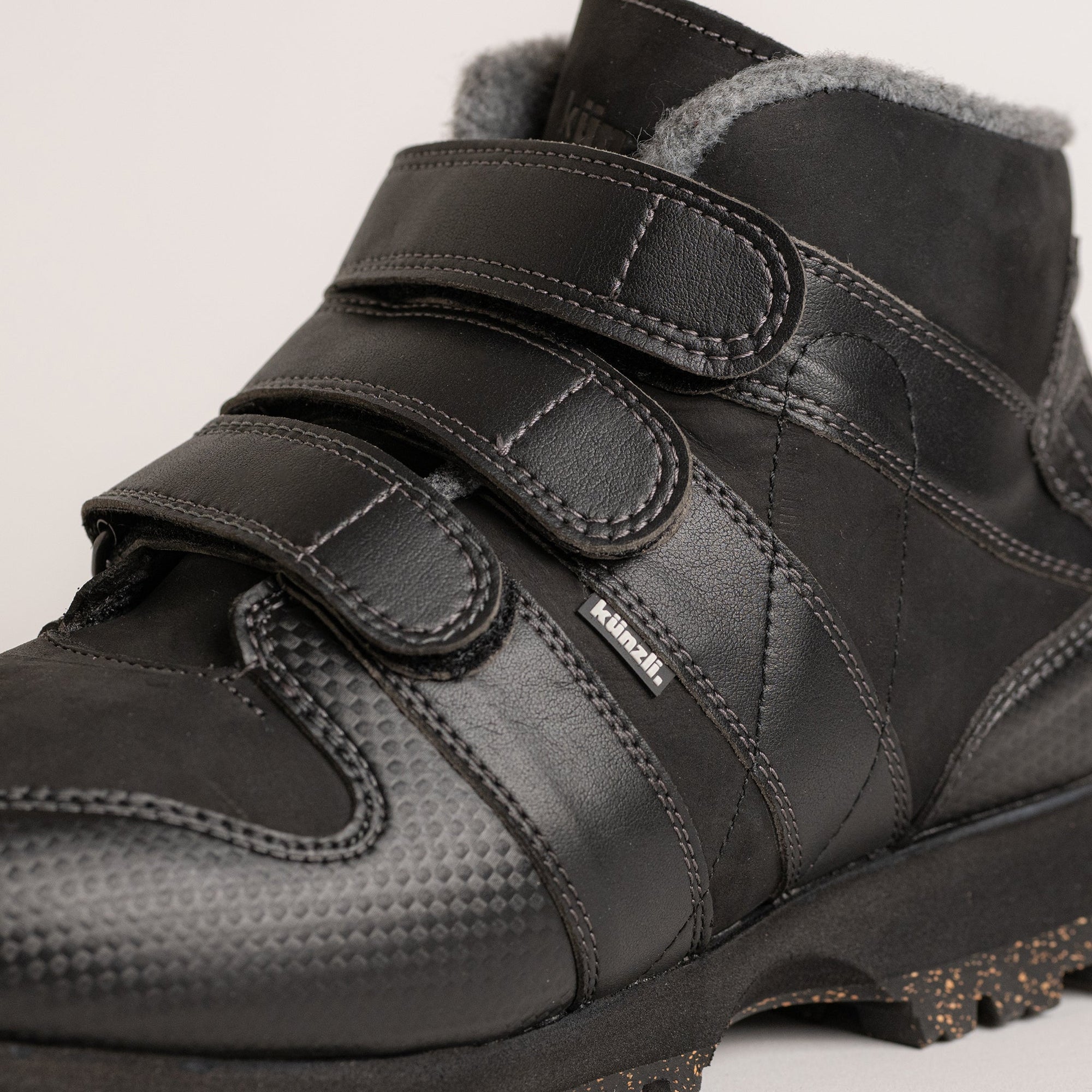 Ein schwarzer Kuenzli Schuh mit Klettverschluss und warmem Innenfutter für Winteraktivitäten.