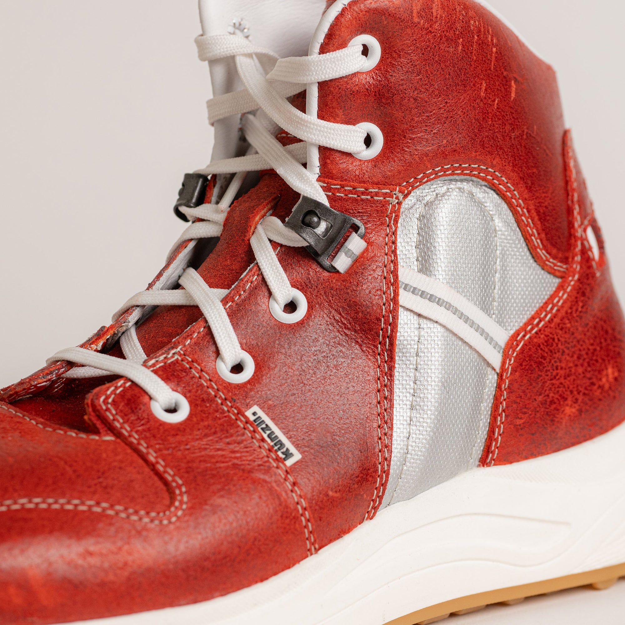 Roter Kuenzli Schuh aus Leder mit weißen Schnürsenkeln und silbernen Details.