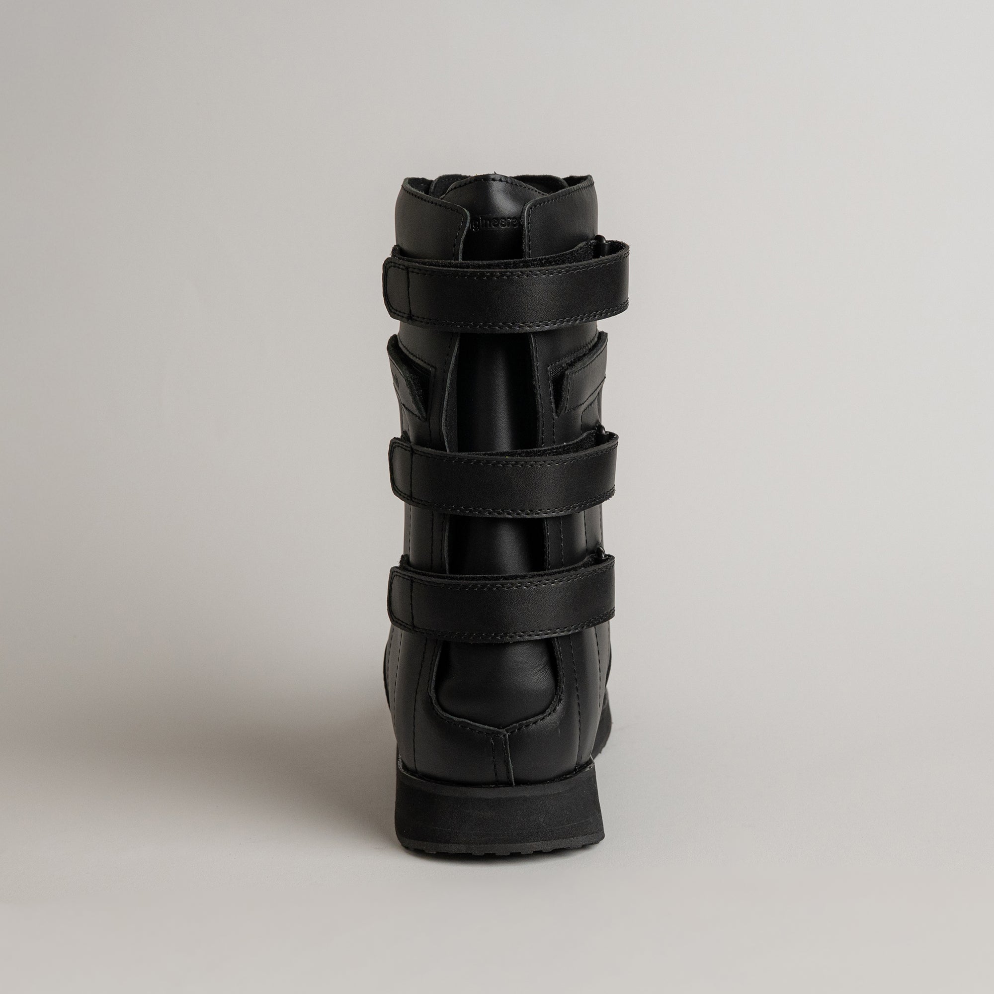 Schwarzer Lederstiefel von Kuenzli Schuhe mit Klettverschlüssen auf grauem Hintergrund.