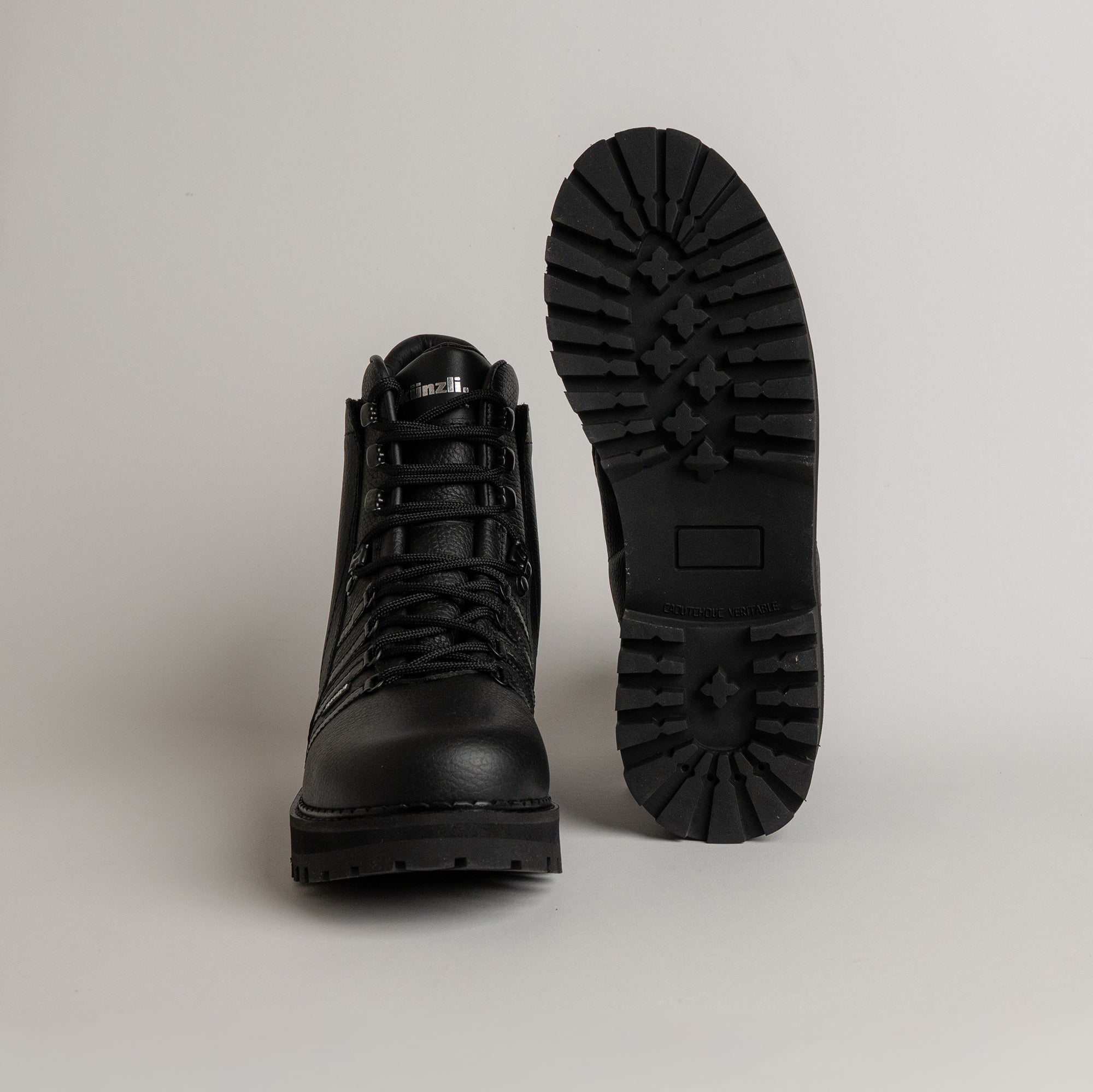 Schwarze Kuenzli Schuhe aus Leder mit robuster Profilsohle auf grauem Hintergrund.