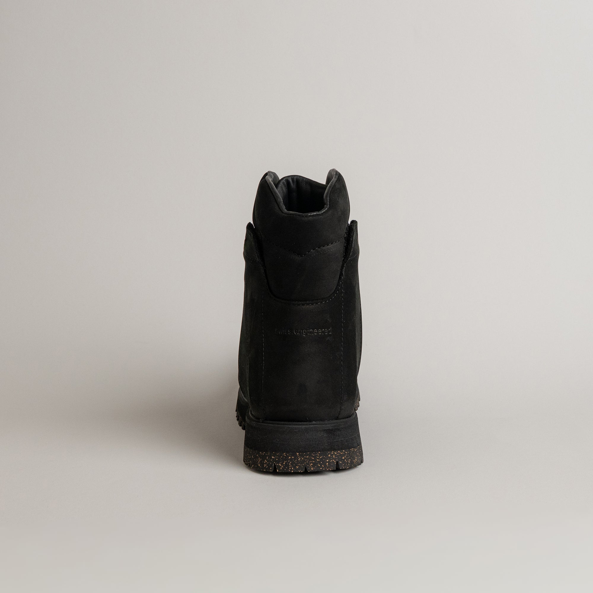 Ein schwarzer Stiefel von Kuenzli Schuhe aus Leder, Rückansicht auf grauem Hintergrund.