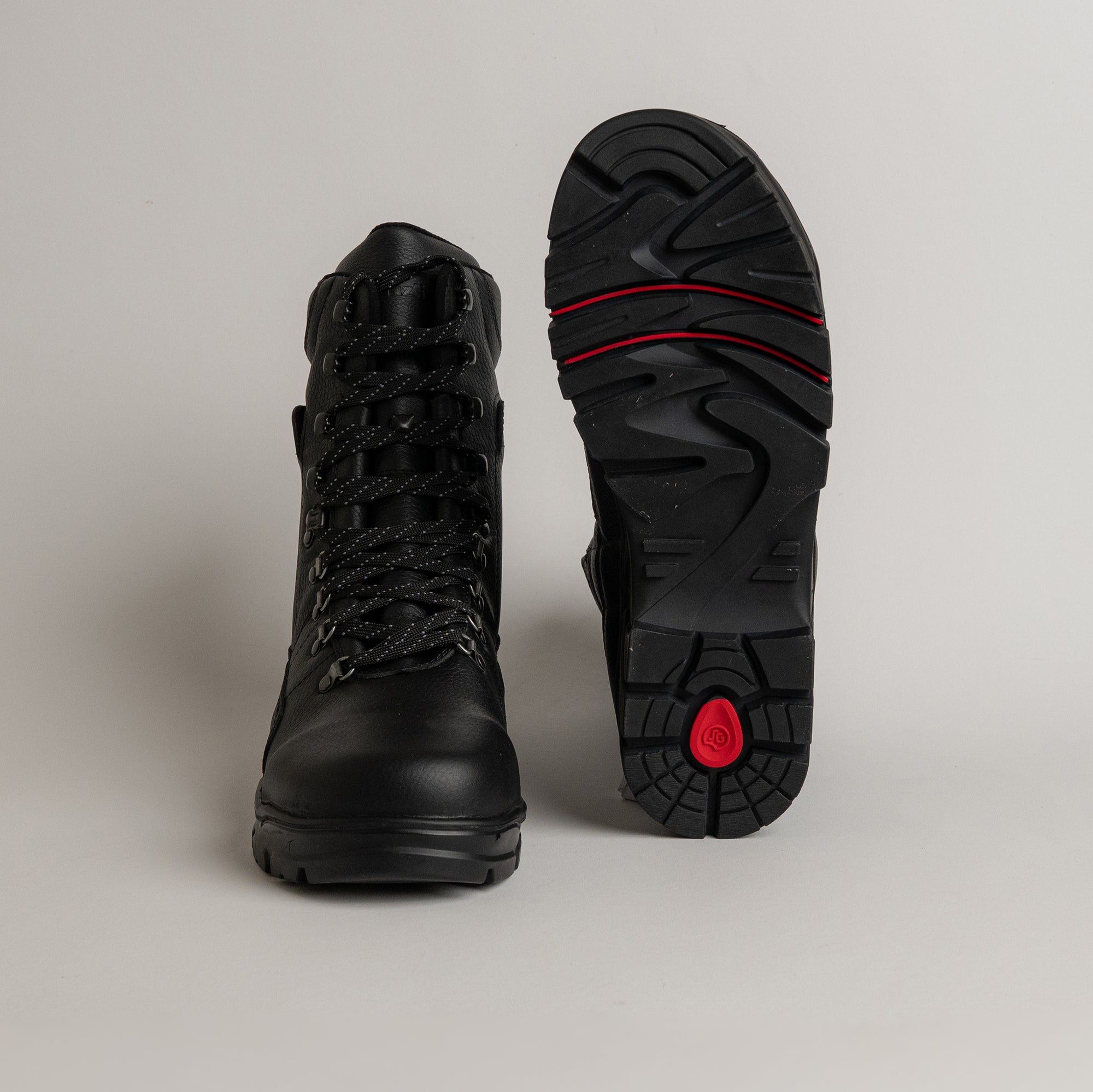 Schwarze Wanderschuhe von Kuenzli Schuhe mit robuster Sohle und Schnürung auf grauem Hintergrund.