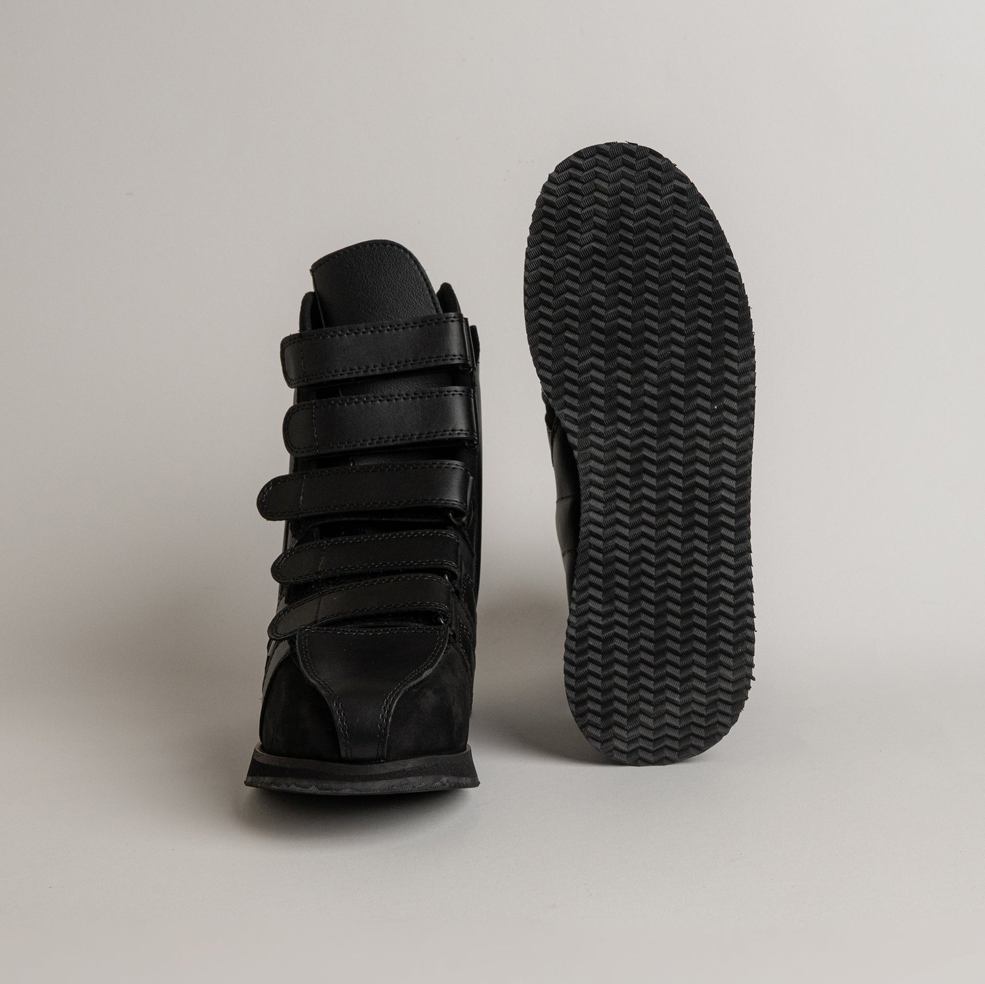 Schwarzer orthopädischer Schuh von Kuenzli Schuhe mit Klettverschlüssen auf grauem Hintergrund.