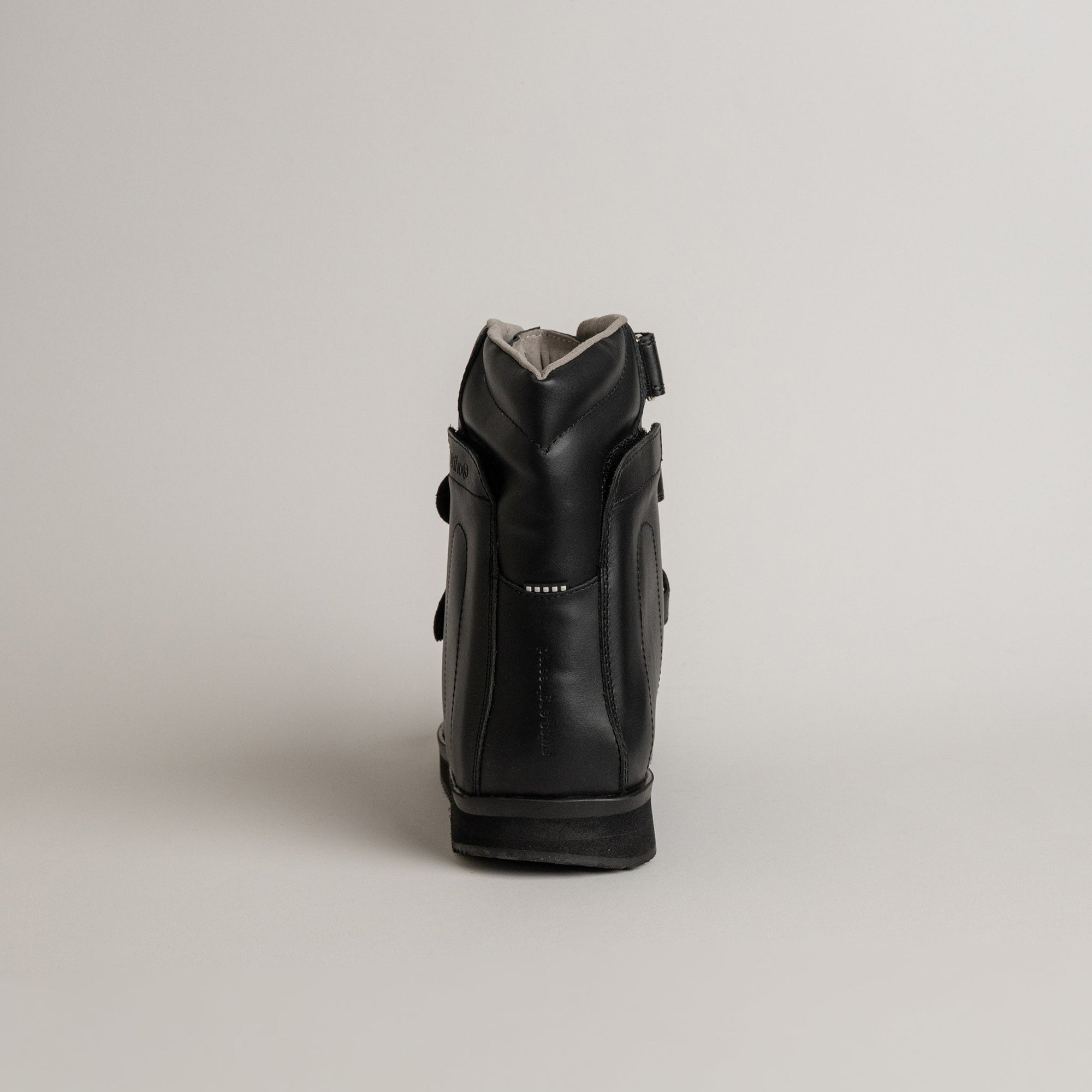 Schwarze Kuenzli Schuhe Orthosandale aus Leder, Rückansicht, auf grauem Hintergrund.