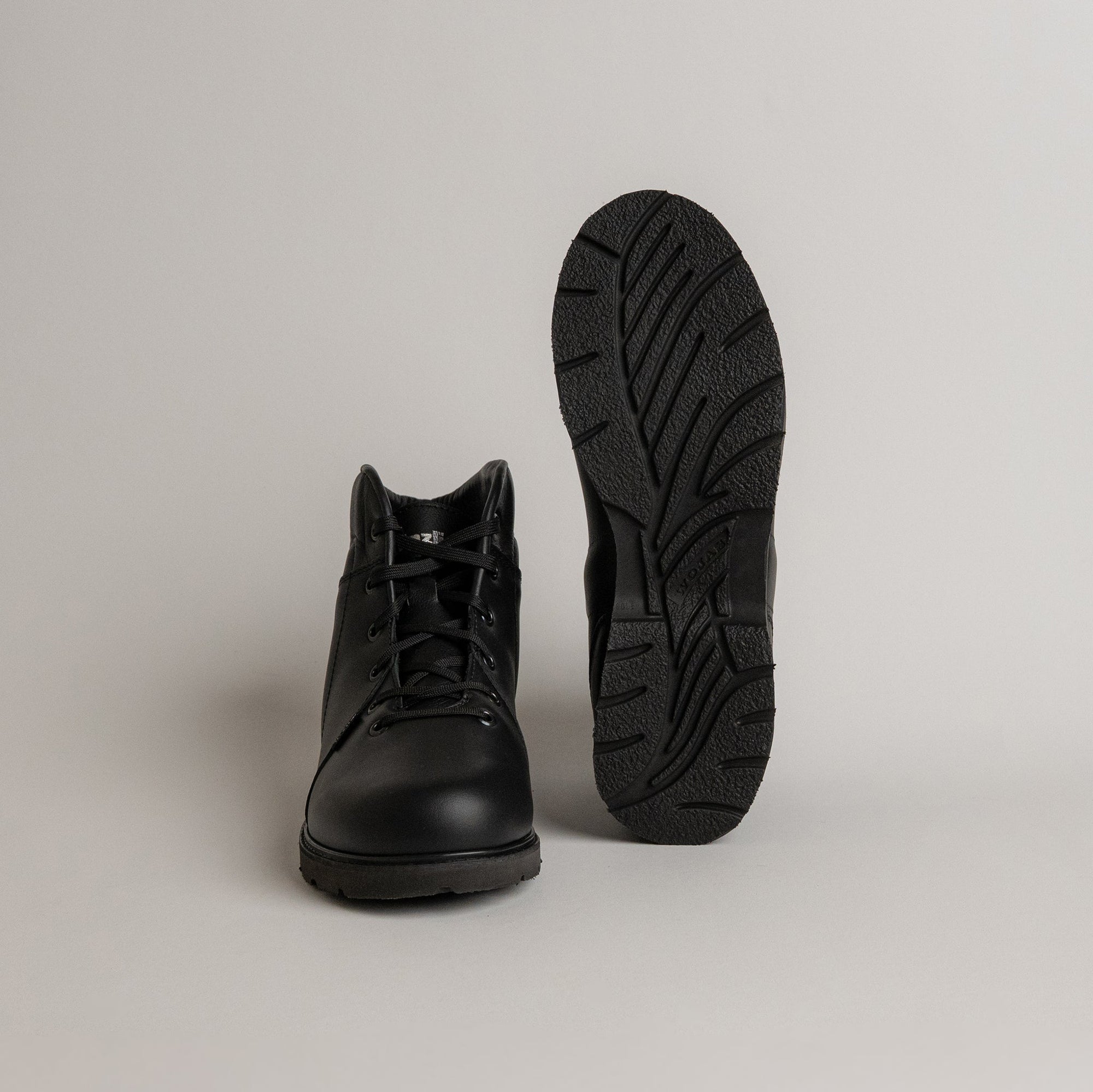 Schwarzer Kuenzli Schuhe Stiefel mit robustem Profil auf grauem Hintergrund.