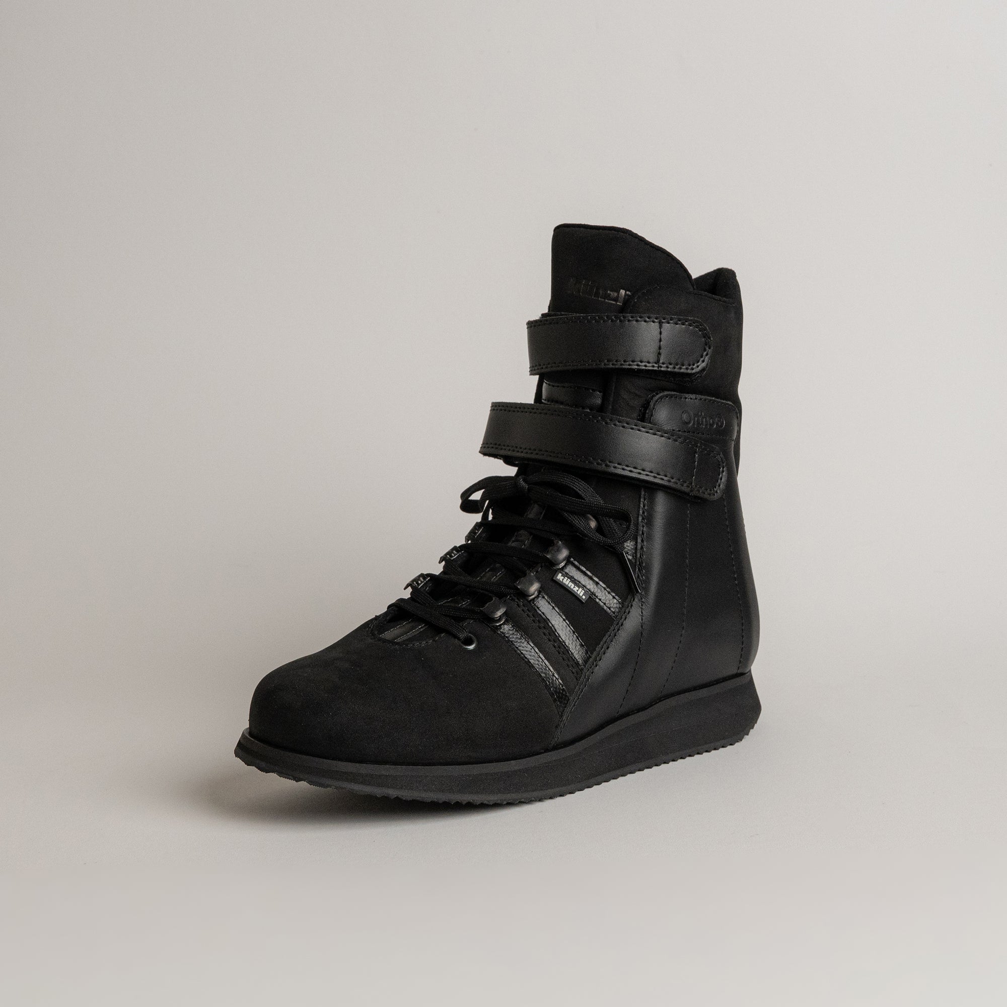 Schwarzer Lederstiefel von Kuenzli Schuhe mit Schnürung und Klettverschluss auf grauem Hintergrund.