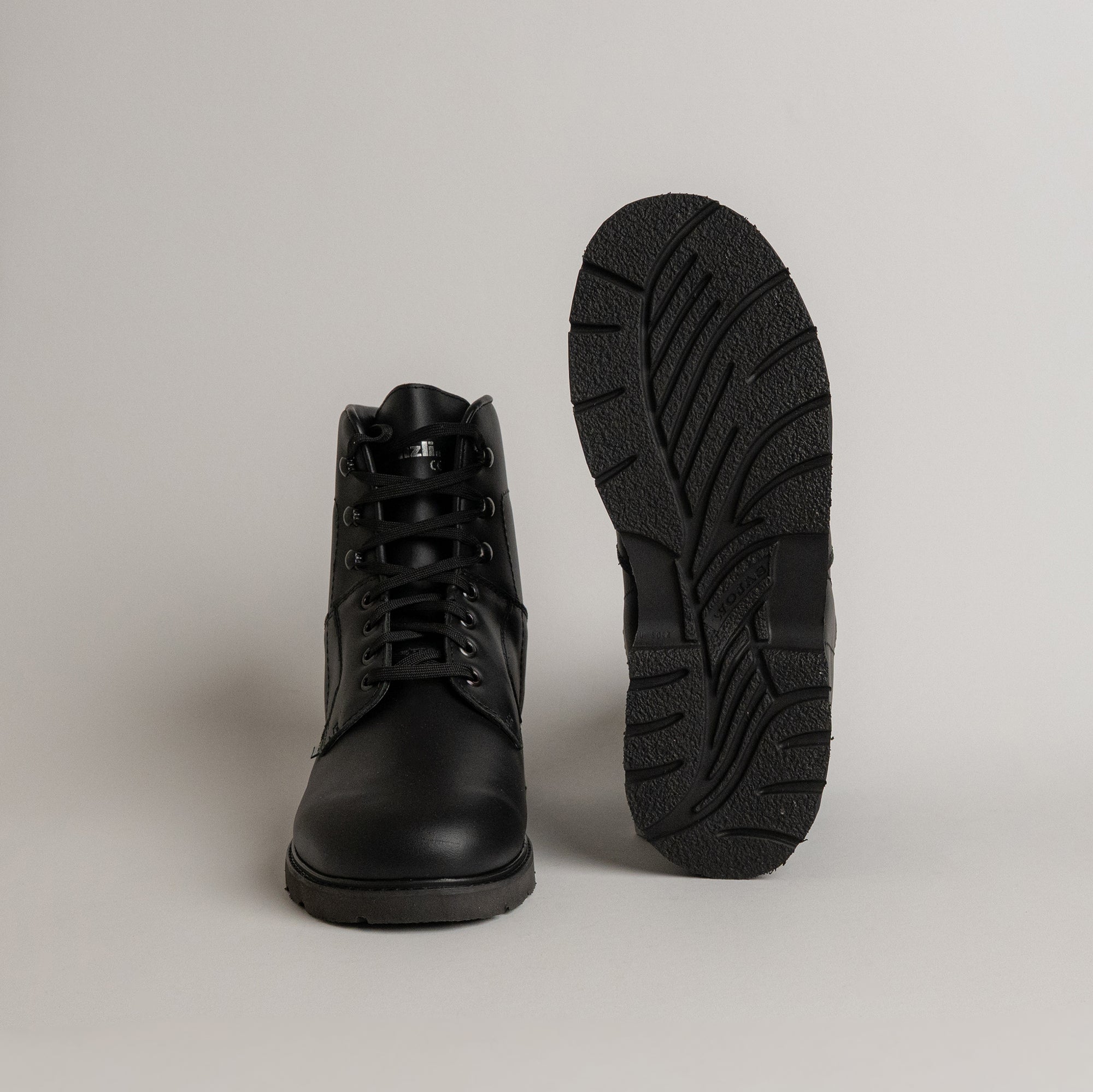 Schwarze Lederstiefel von Kuenzli Schuhe mit robuster Sohle auf grauem Hintergrund.