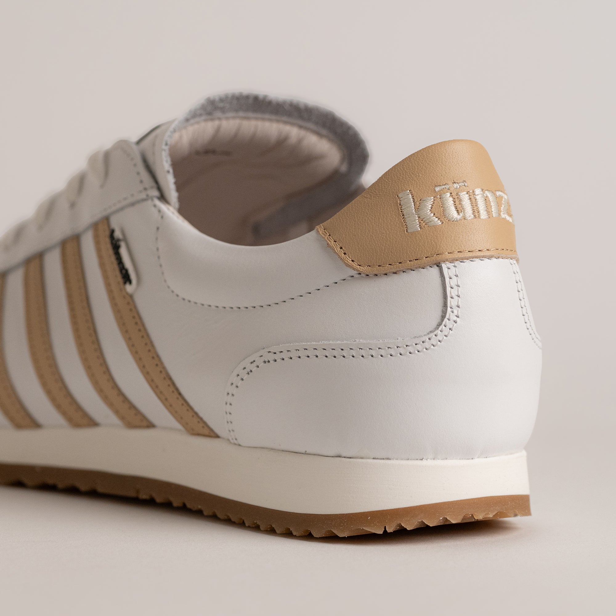 Weißer Kuenzli Schuh mit beigem Lederdetail und gestreiftem Design auf hellem Hintergrund.