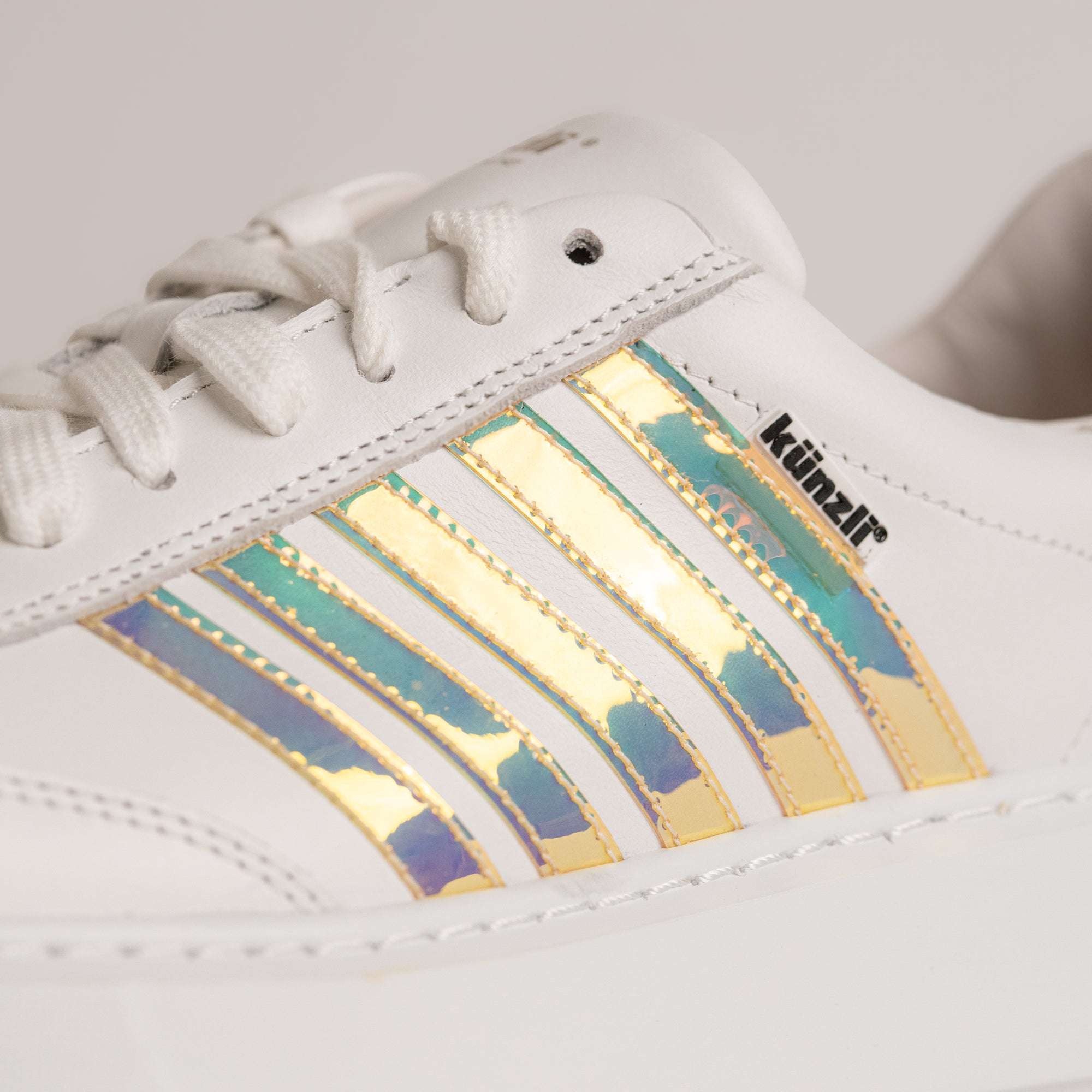 Weißer Kuenzli Schuh mit schillernden Streifen und Logo, ideal für modische Auftritte.