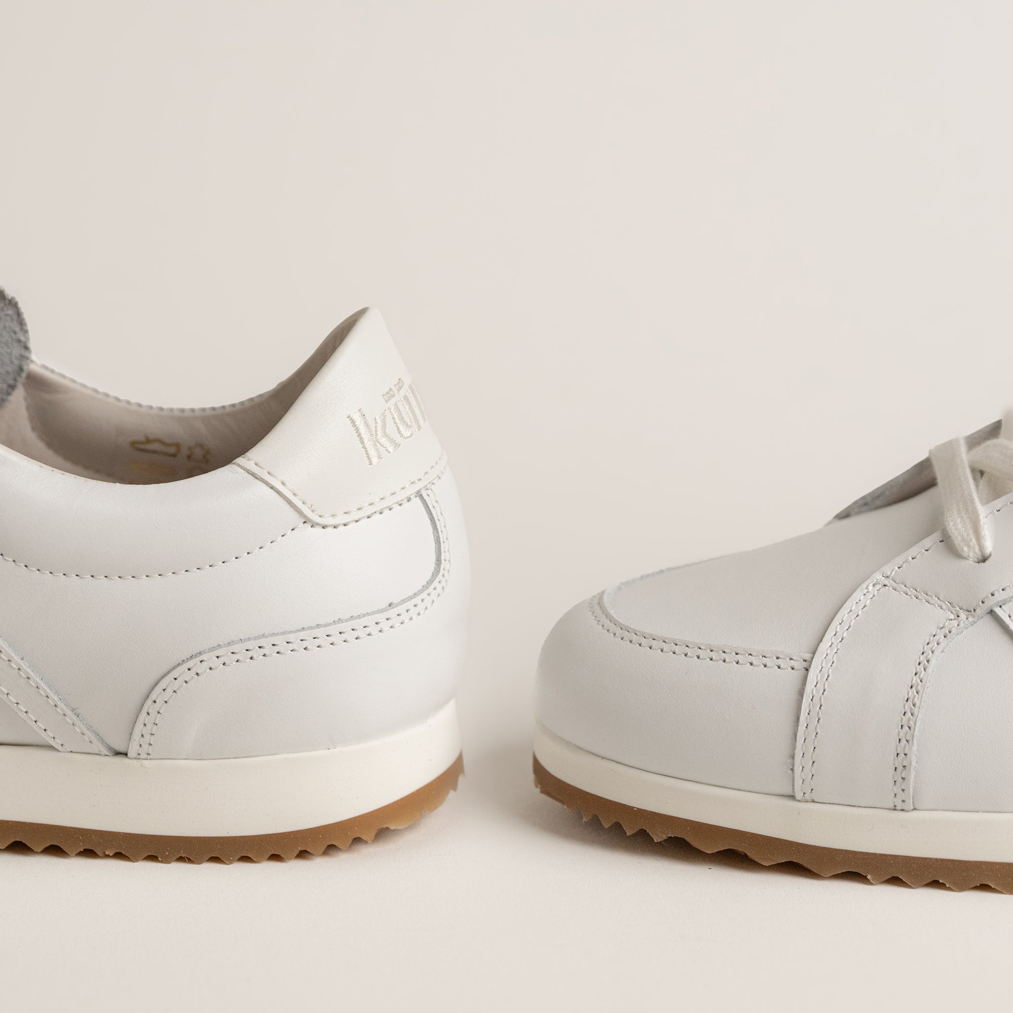 Weiße Lederschuhe von Kuenzli Schuhe mit brauner Sohle auf hellem Hintergrund.