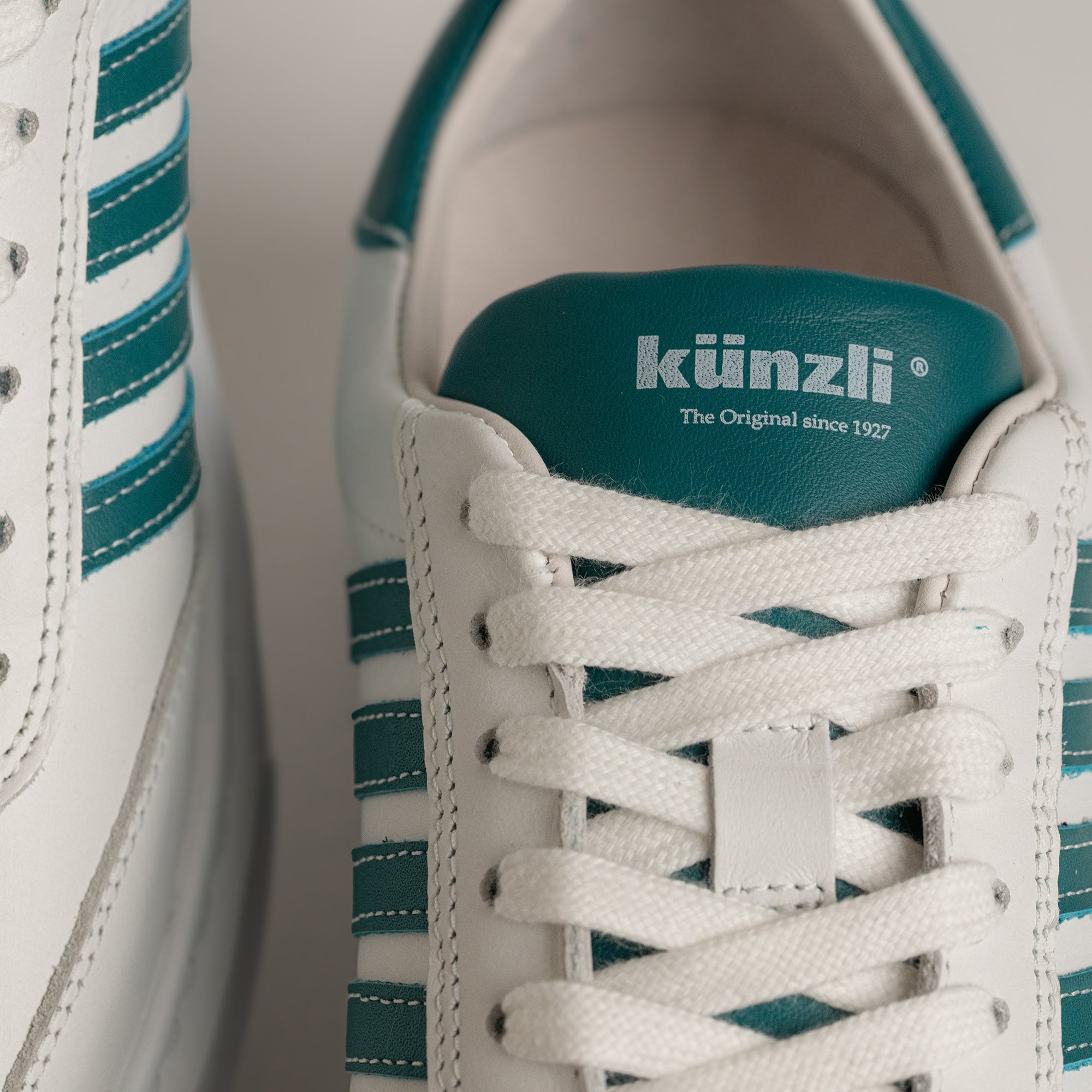 Weiße Kuenzli Schuhe mit grünen Streifen und Logo auf der Zunge, aus Leder.