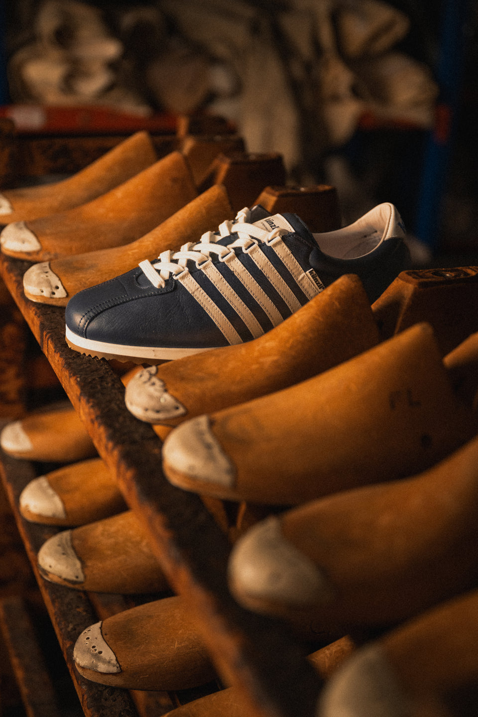 Ein blauer Kuenzli Schuh liegt auf traditionellen Holzschuhleisten in einer Werkstatt.