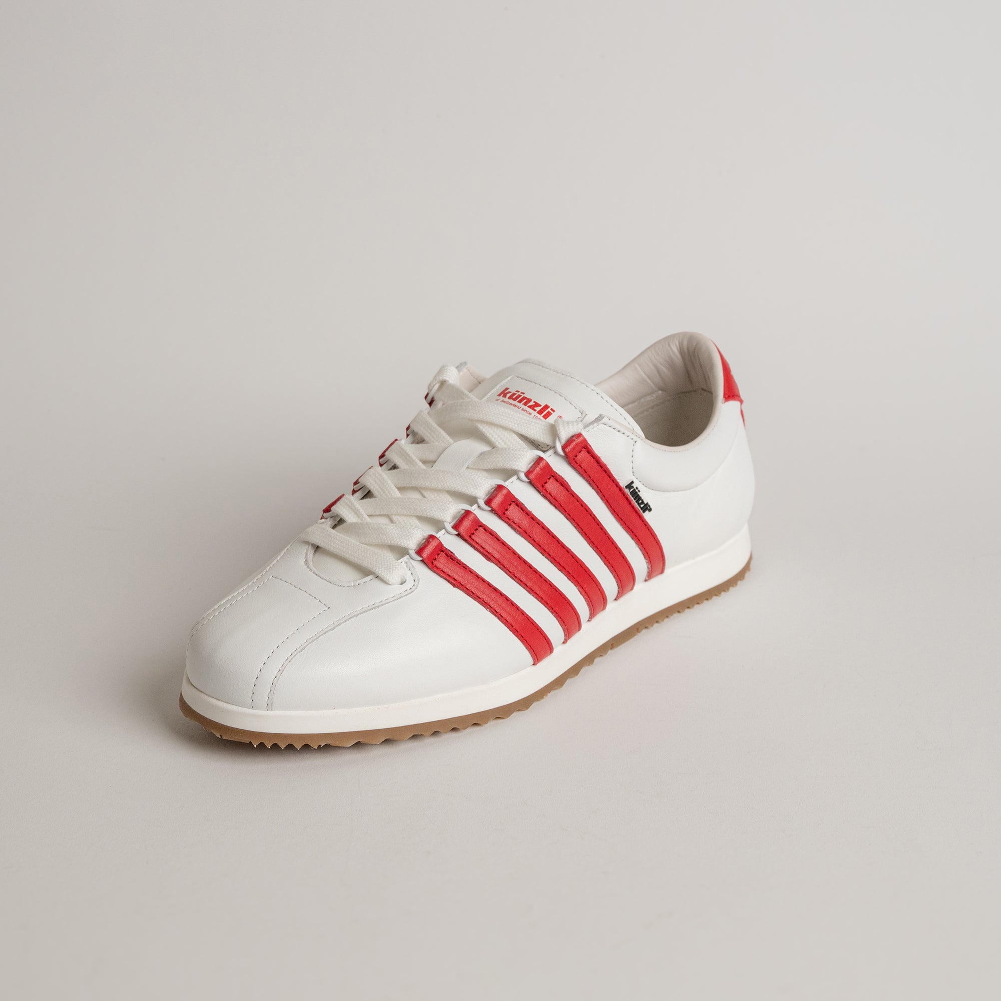 Weißer Kuenzli Schuh mit roten Streifen auf hellem Hintergrund.
