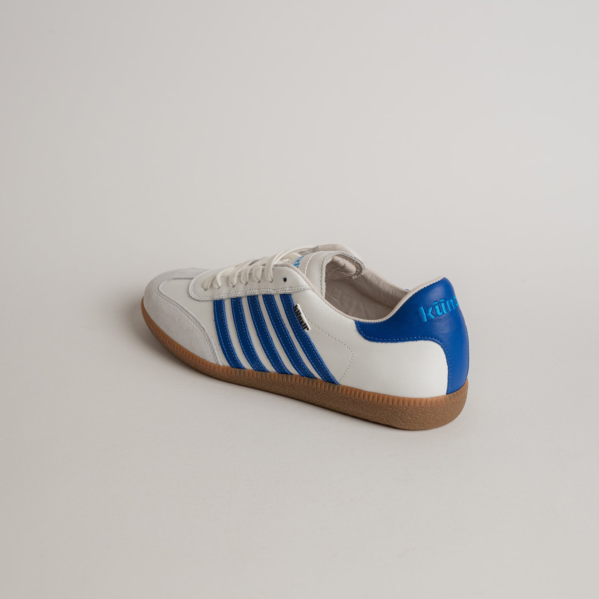 Weiß-blauer Sportschuh von Kuenzli Schuhe auf hellem Hintergrund, ideal für Indoor-Training.