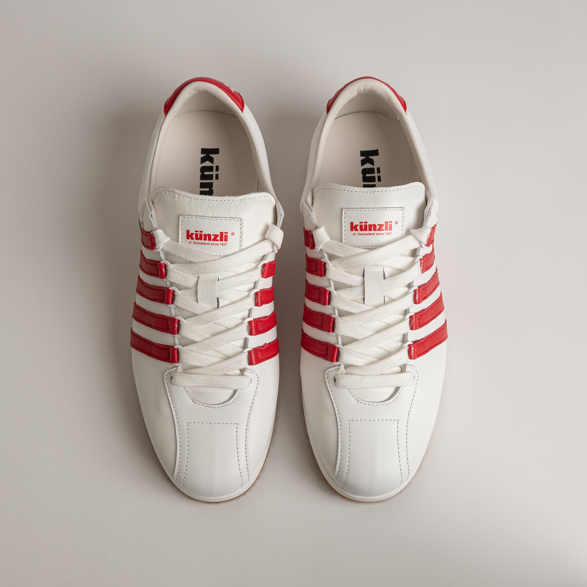 Weiße Kuenzli Schuhe mit roten Streifen, ideal für sportliche Aktivitäten und Freizeit.